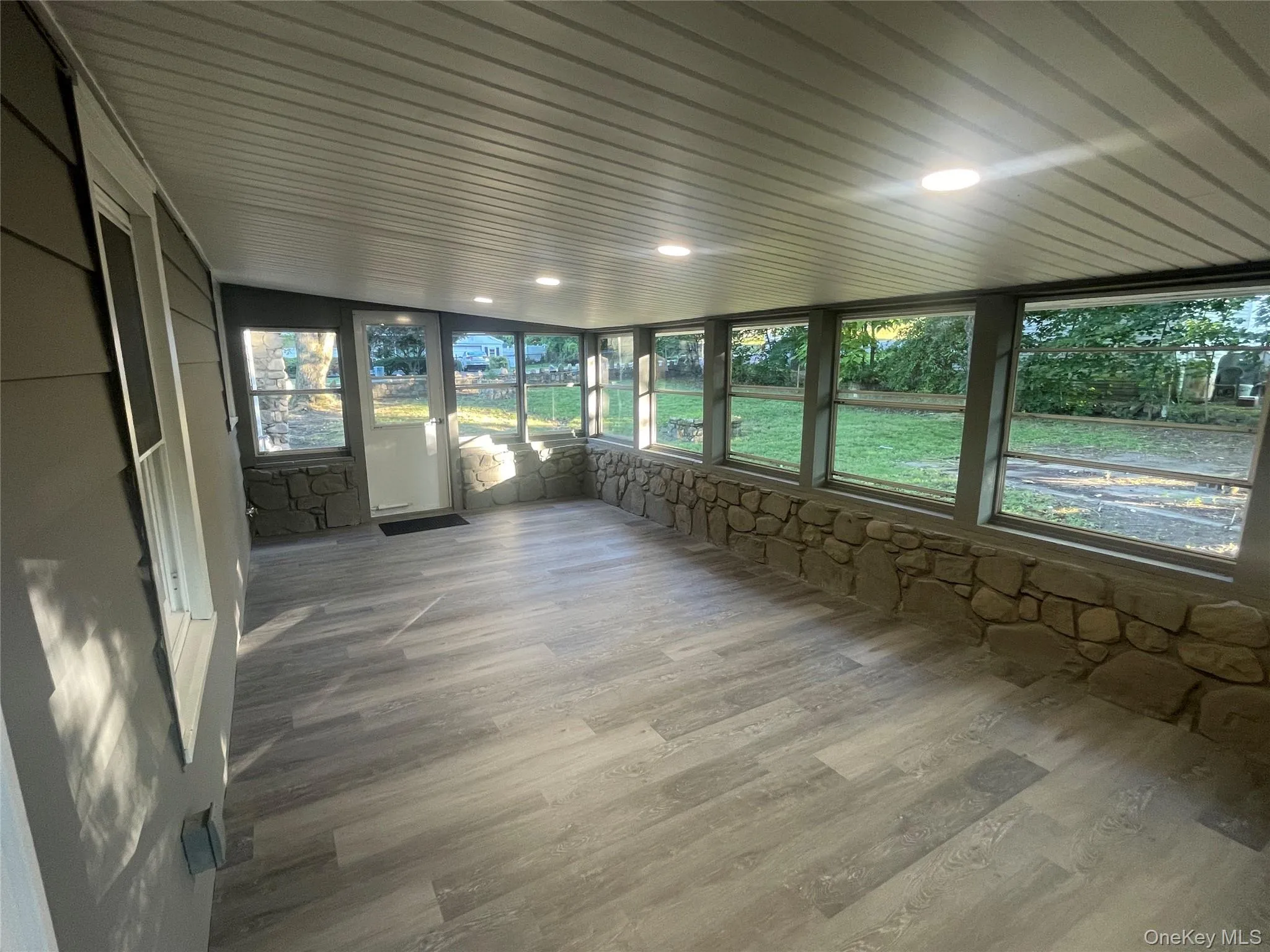 Unfurnished sunroom featuring wood finished floors and recessed lighting Unfurnished sunroom featuring wood finished floors and recessed lighting