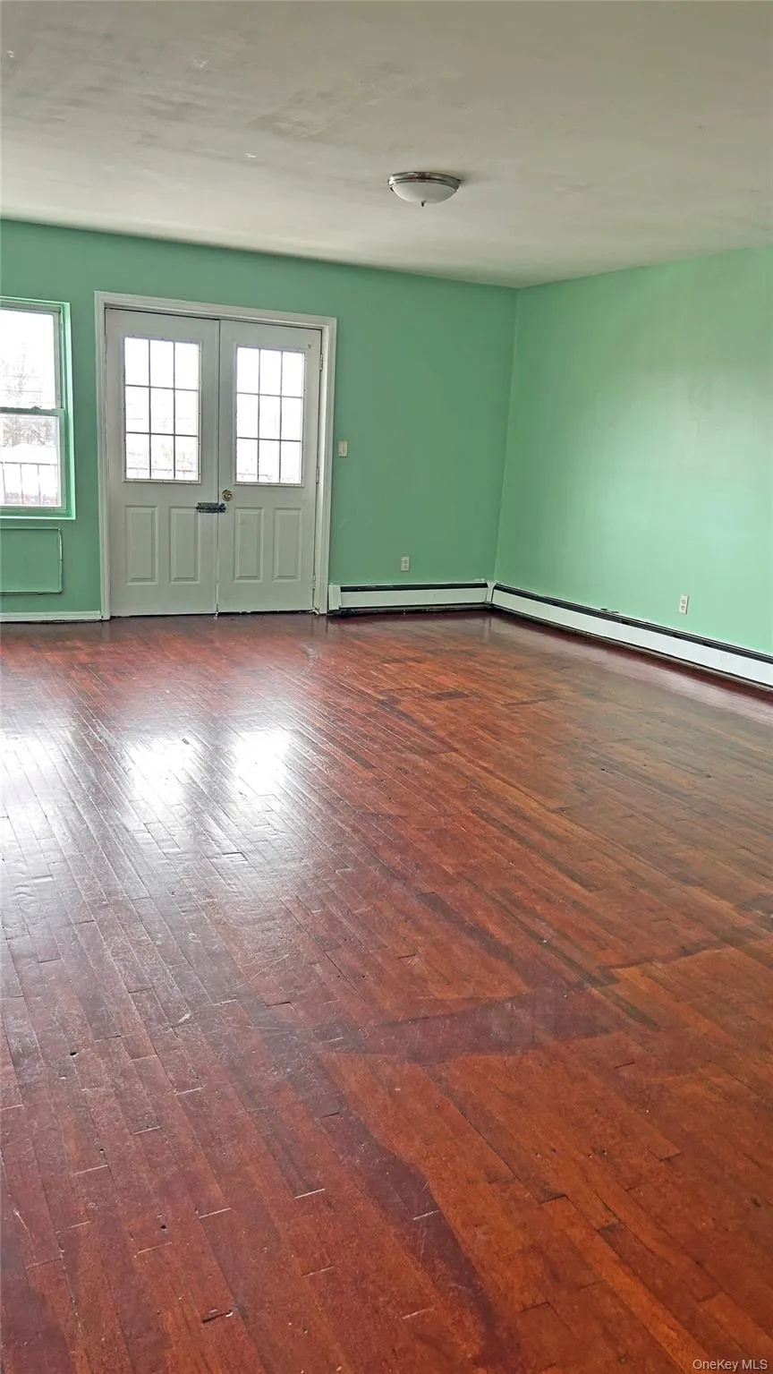 Spare room with dark wood finished floors and a baseboard radiator Spare room with dark wood finished floors and a baseboard radiator