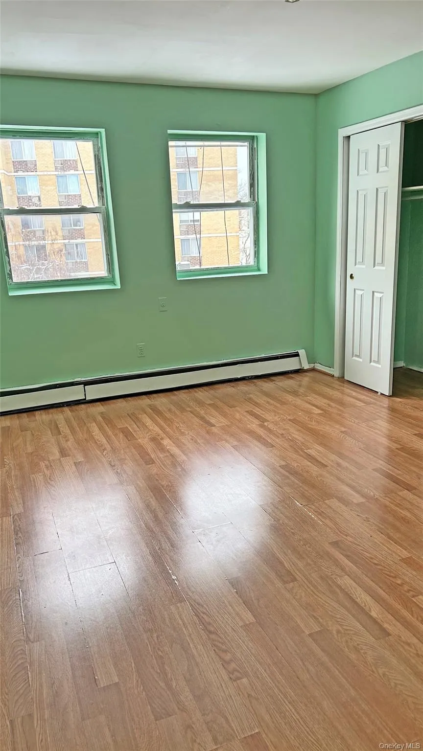 Unfurnished room with a baseboard radiator and wood finished floors Unfurnished room with a baseboard radiator and wood finished floors