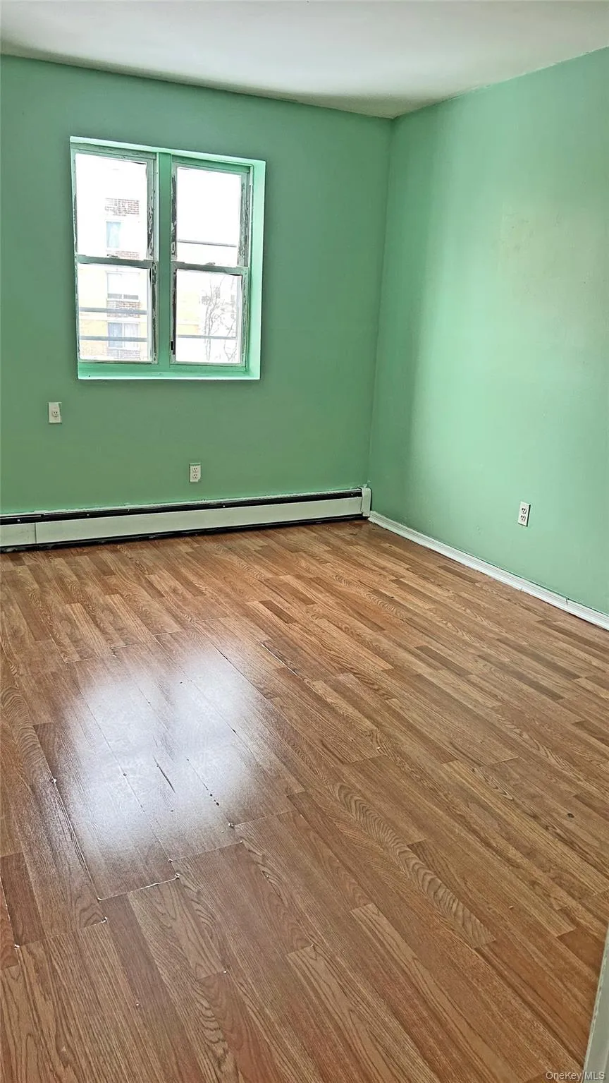 Empty room featuring a baseboard heating unit and wood-type flooring Empty room featuring a baseboard heating unit and wood-type flooring