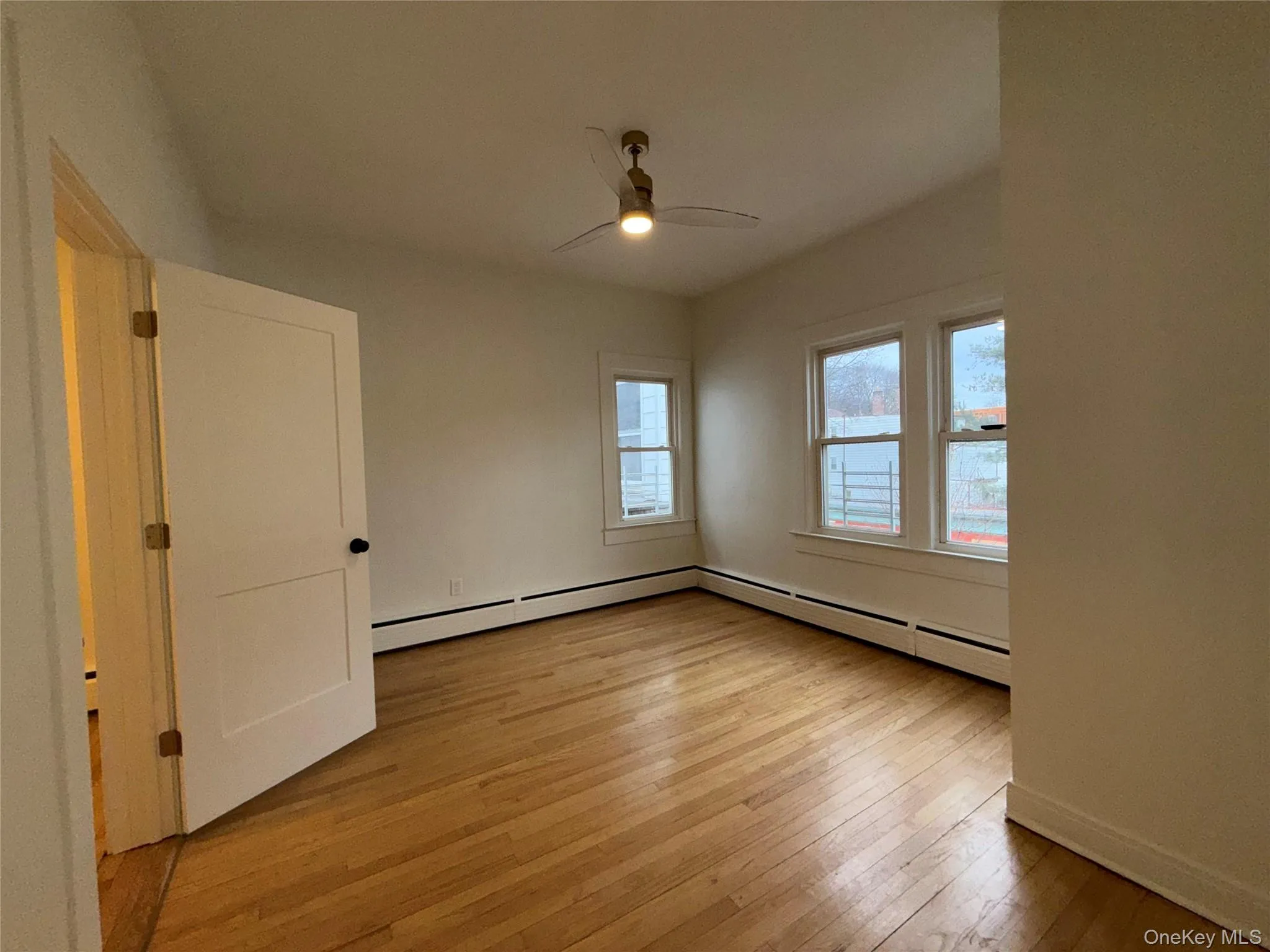 Unfurnished room with light wood-style flooring, baseboard heating, and ceiling fan Unfurnished room with light wood-style flooring, baseboard heating, and ceiling fan