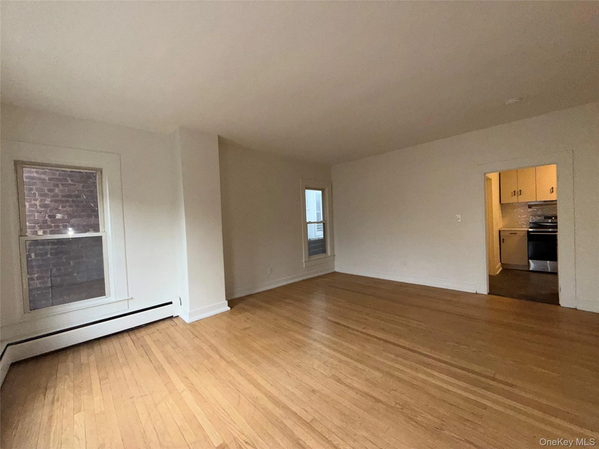 Unfurnished room with light wood finished floors and a baseboard heating unit Unfurnished room with light wood finished floors and a baseboard heating unit