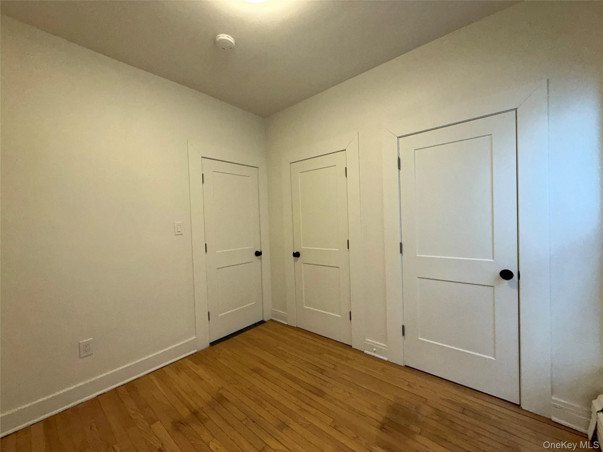 Unfurnished bedroom featuring hardwood / wood-style flooring and baseboards Unfurnished bedroom featuring hardwood / wood-style flooring and baseboards