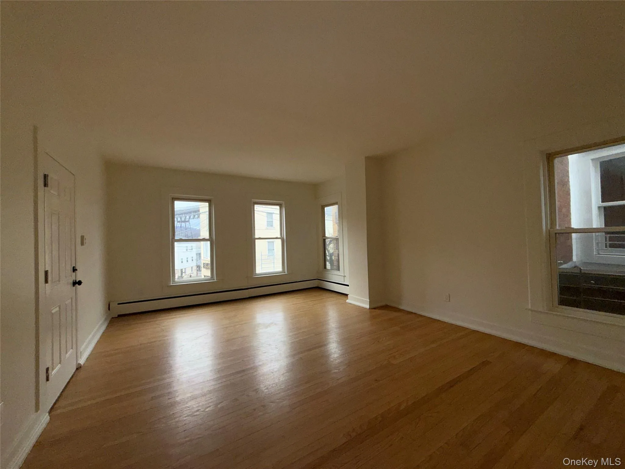 Unfurnished room with light wood-style floors and baseboard heating Unfurnished room with light wood-style floors and baseboard heating