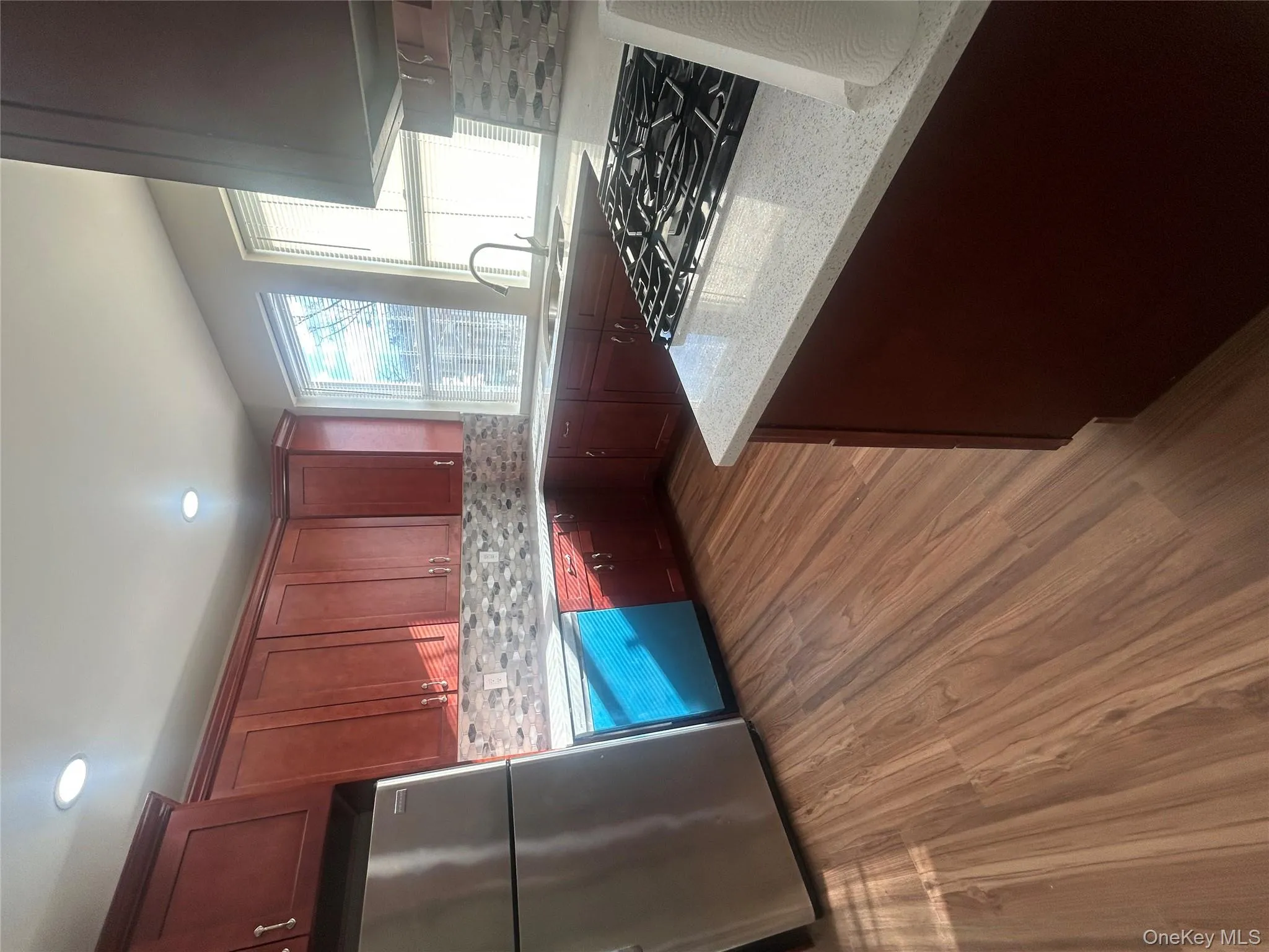 Kitchen featuring refrigerator, light stone countertops, dishwasher, dark wood-style flooring, and decorative backsplash Kitchen featuring refrigerator, light stone countertops, dishwasher, dark wood-style flooring, and decorative backsplash