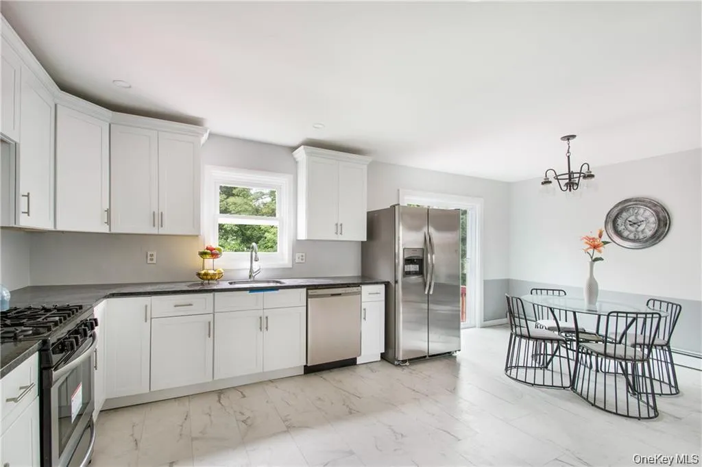 Kitchen with stainless steel appliances, light marble finish floors, white cabinetry, a chandelier, and decorative light fixtures Kitchen with stainless steel appliances, light marble finish floors, white cabinetry, a chandelier, and decorative light fixtures