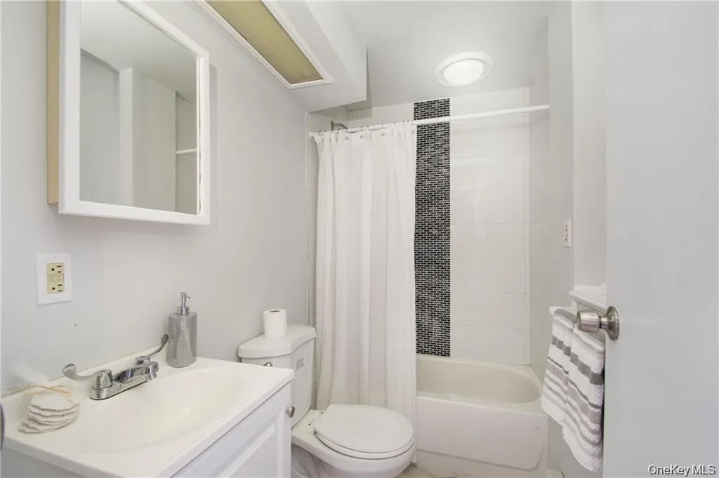 Full bathroom featuring vanity and shower / bath combo with shower curtain Full bathroom featuring vanity and shower / bath combo with shower curtain