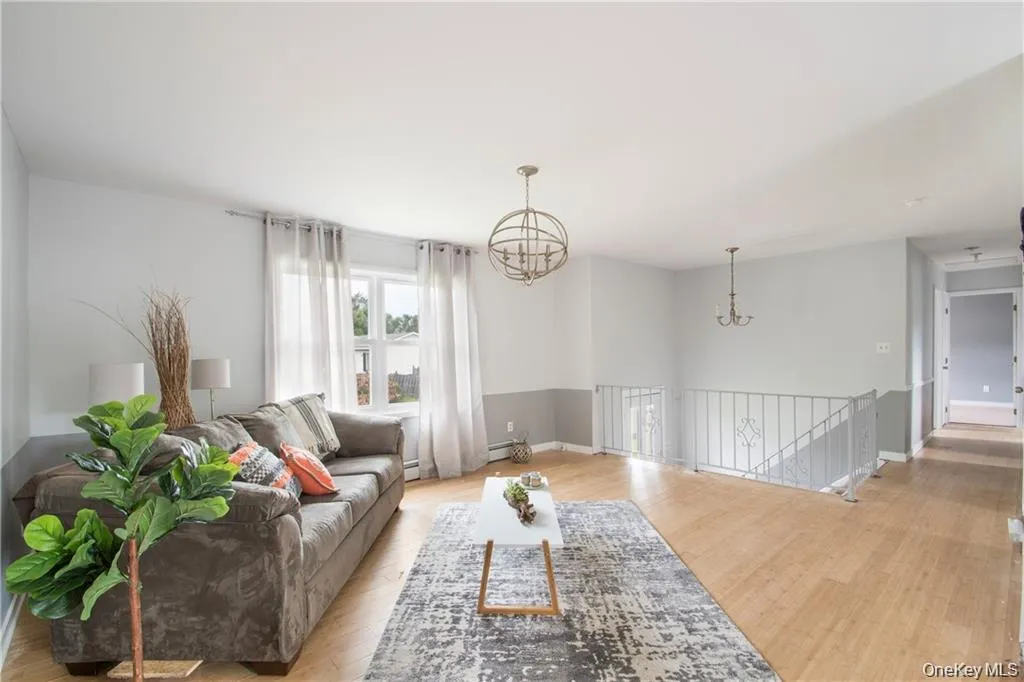 Living room featuring a chandelier, light wood-style flooring, and wainscoting Living room featuring a chandelier, light wood-style flooring, and wainscoting