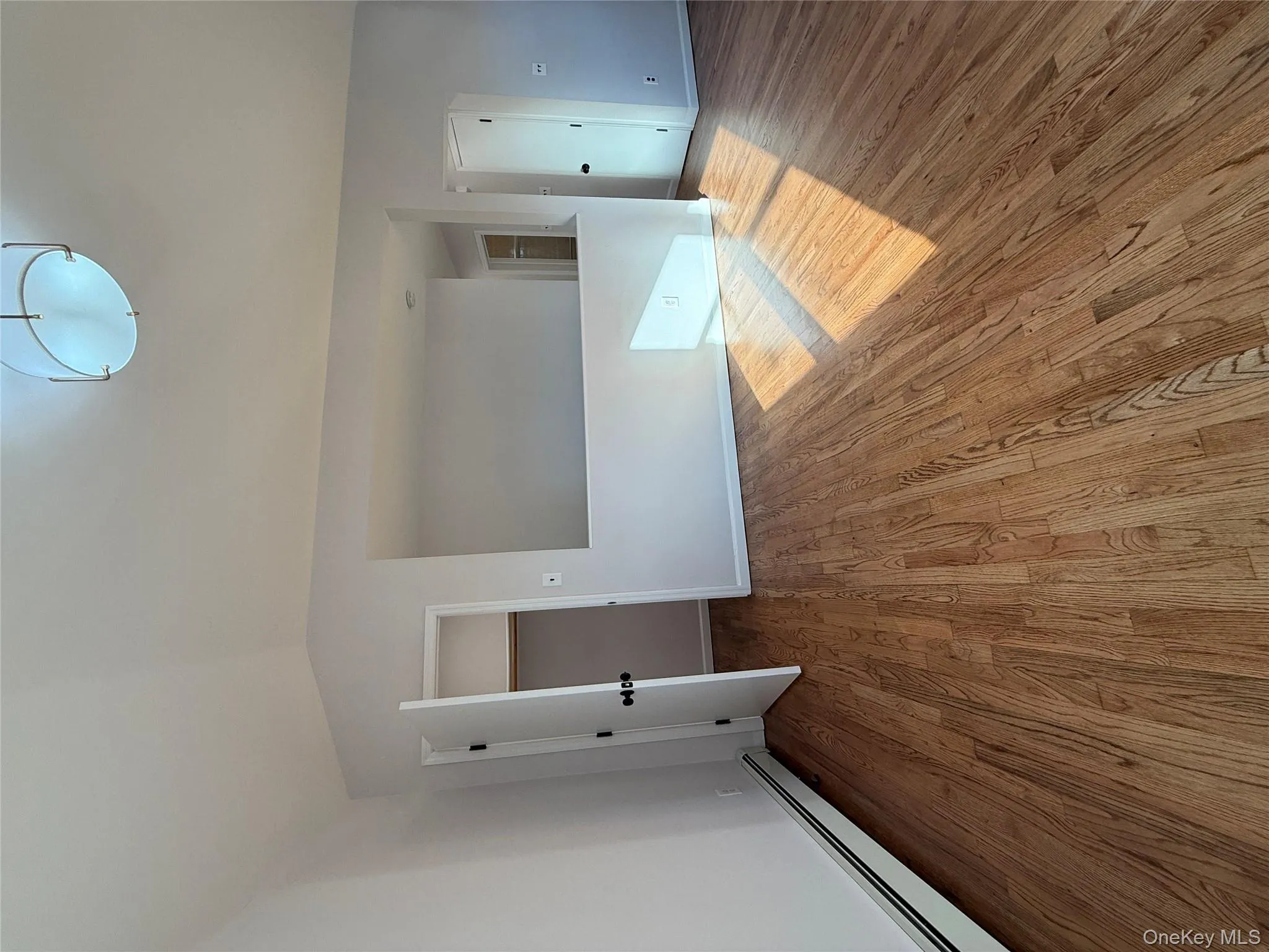 Spare room featuring a baseboard radiator, light wood-style floors, and lofted ceiling Spare room featuring a baseboard radiator, light wood-style floors, and lofted ceiling