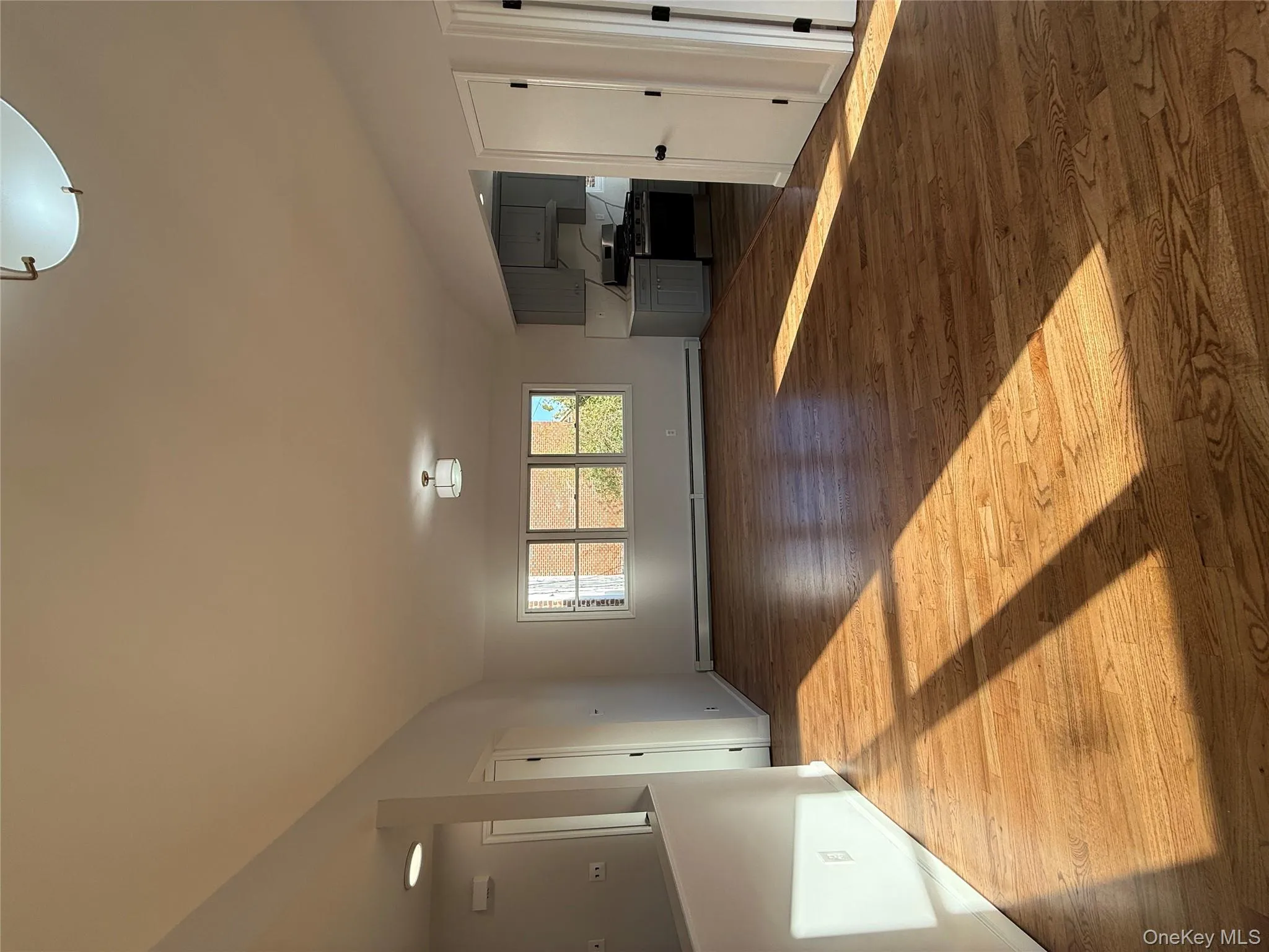 Unfurnished living room featuring dark wood-style flooring and a baseboard radiator Unfurnished living room featuring dark wood-style flooring and a baseboard radiator