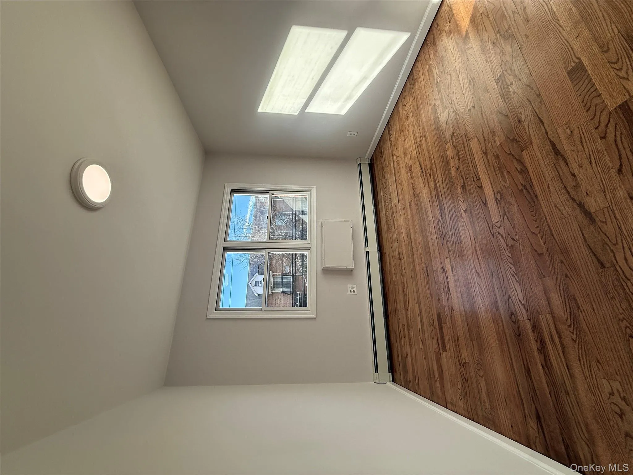 Unfurnished room with a baseboard heating unit and hardwood / wood-style flooring Unfurnished room with a baseboard heating unit and hardwood / wood-style flooring