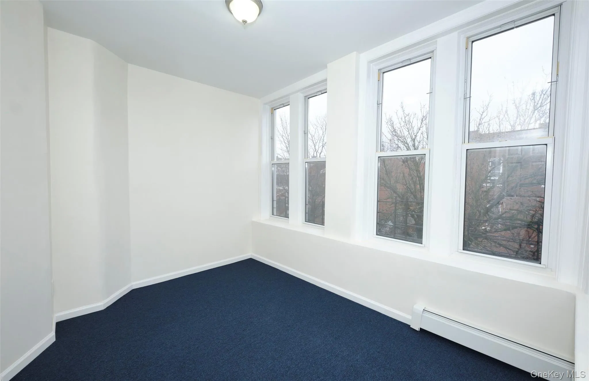 Unfurnished room featuring baseboard heating and dark carpet Unfurnished room featuring baseboard heating and dark carpet