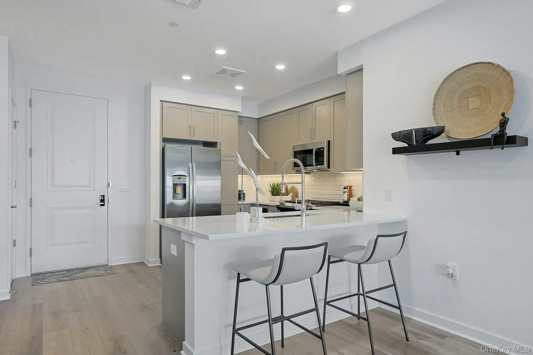 Kitchen with stainless steel appliances, gray cabinetry, a kitchen bar Kitchen with stainless steel appliances, gray cabinetry, a kitchen bar