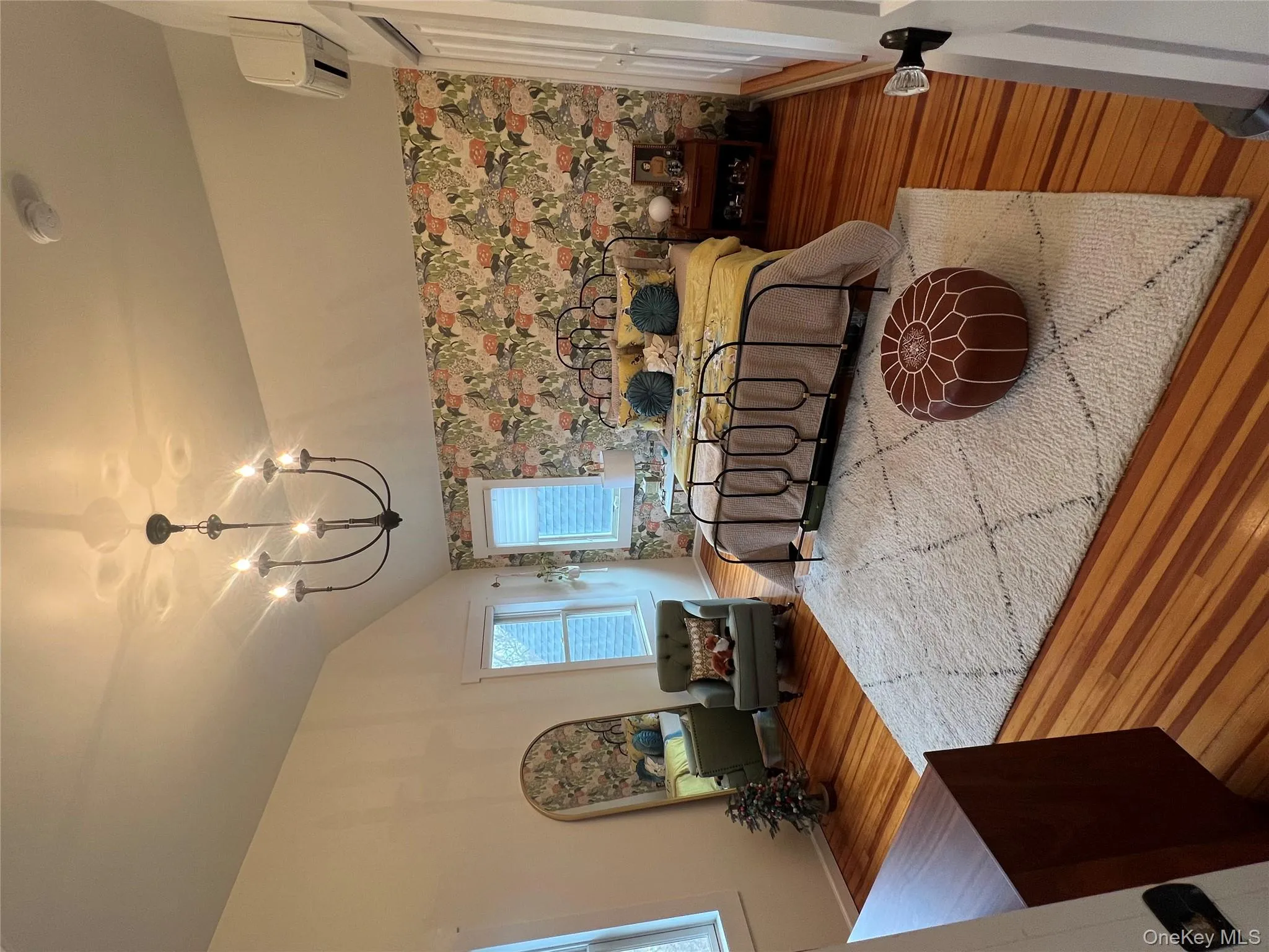 Bedroom featuring wallpapered walls, wood finished floors, an accent wall, vaulted ceiling, and an AC wall unit Bedroom featuring wallpapered walls, wood finished floors, an accent wall, vaulted ceiling, and an AC wall unit