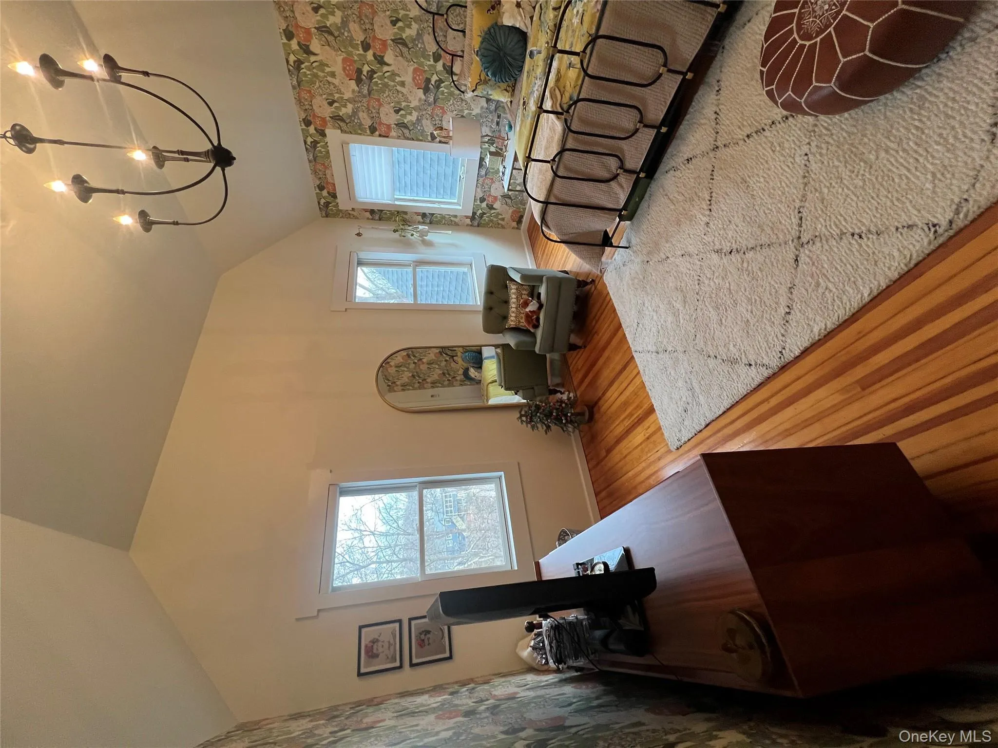 Bedroom with wallpapered walls, light wood-style flooring, vaulted ceiling, a chandelier, and multiple windows Bedroom with wallpapered walls, light wood-style flooring, vaulted ceiling, a chandelier, and multiple windows