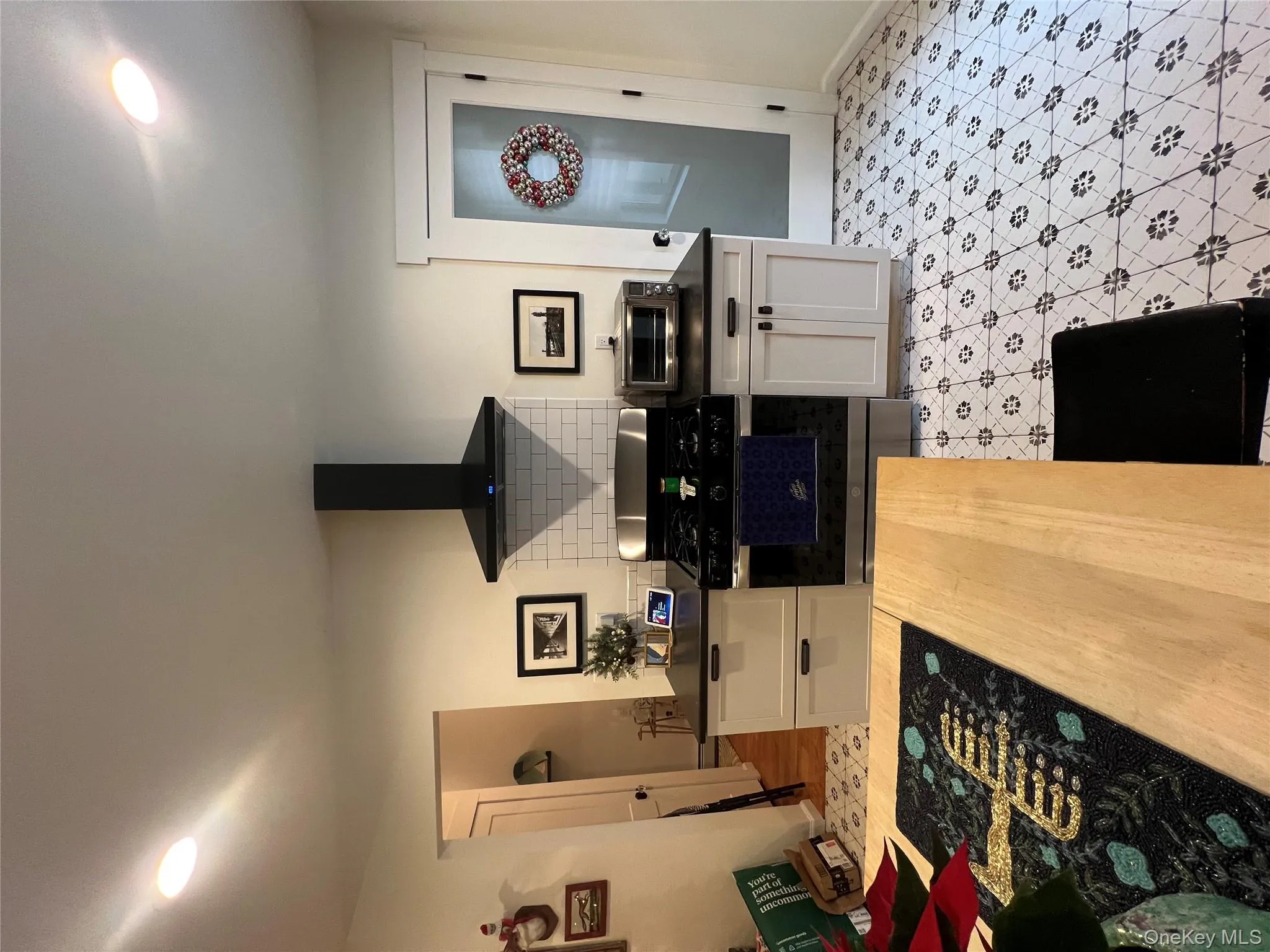 Kitchen featuring recessed lighting, stainless steel stove, exhaust hood, white cabinetry, and light flooring Kitchen featuring recessed lighting, stainless steel stove, exhaust hood, white cabinetry, and light flooring
