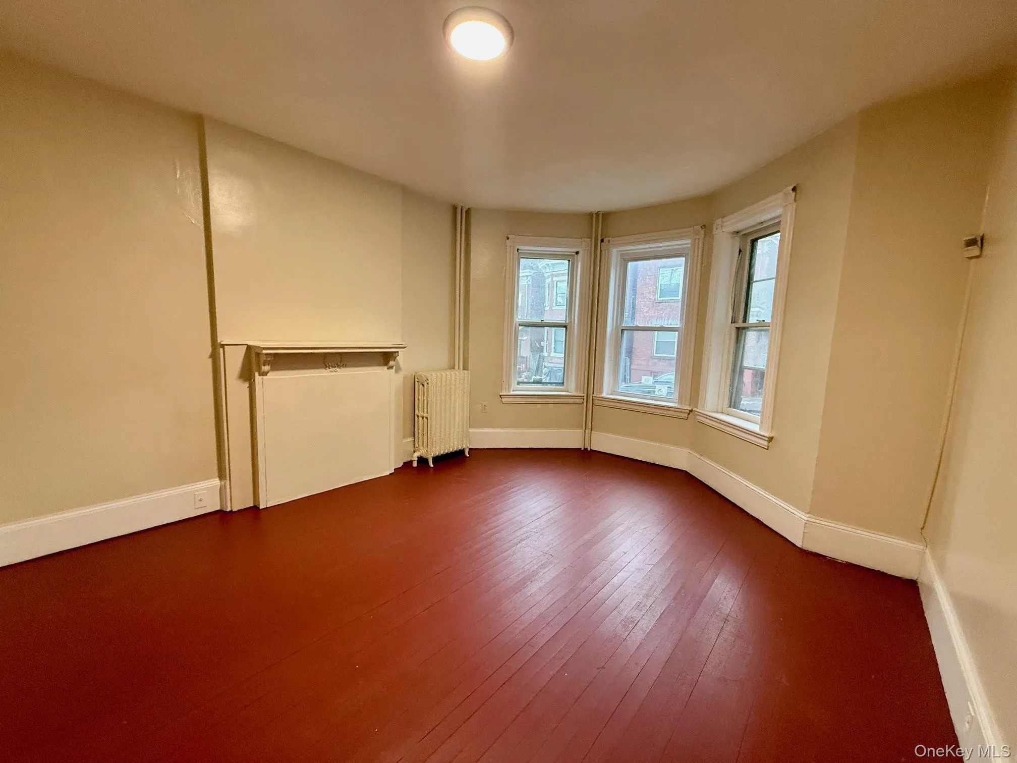 Empty room featuring radiator heating unit and wood-type flooring Empty room featuring radiator heating unit and wood-type flooring