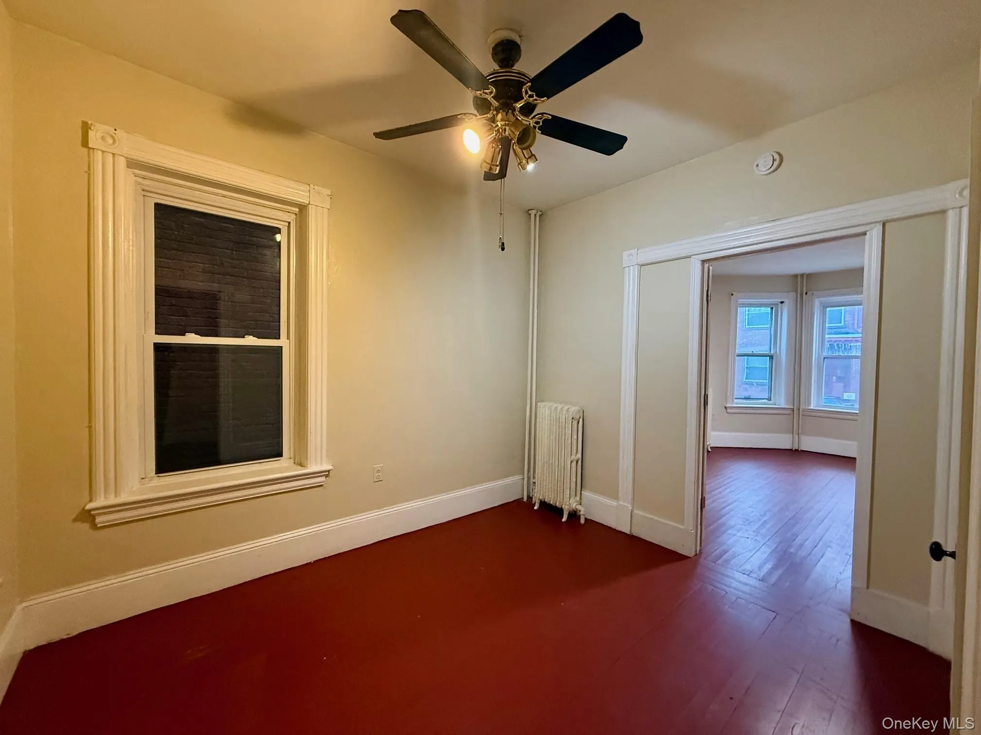 Unfurnished room with radiator heating unit, dark wood-style floors, and a ceiling fan Unfurnished room with radiator heating unit, dark wood-style floors, and a ceiling fan