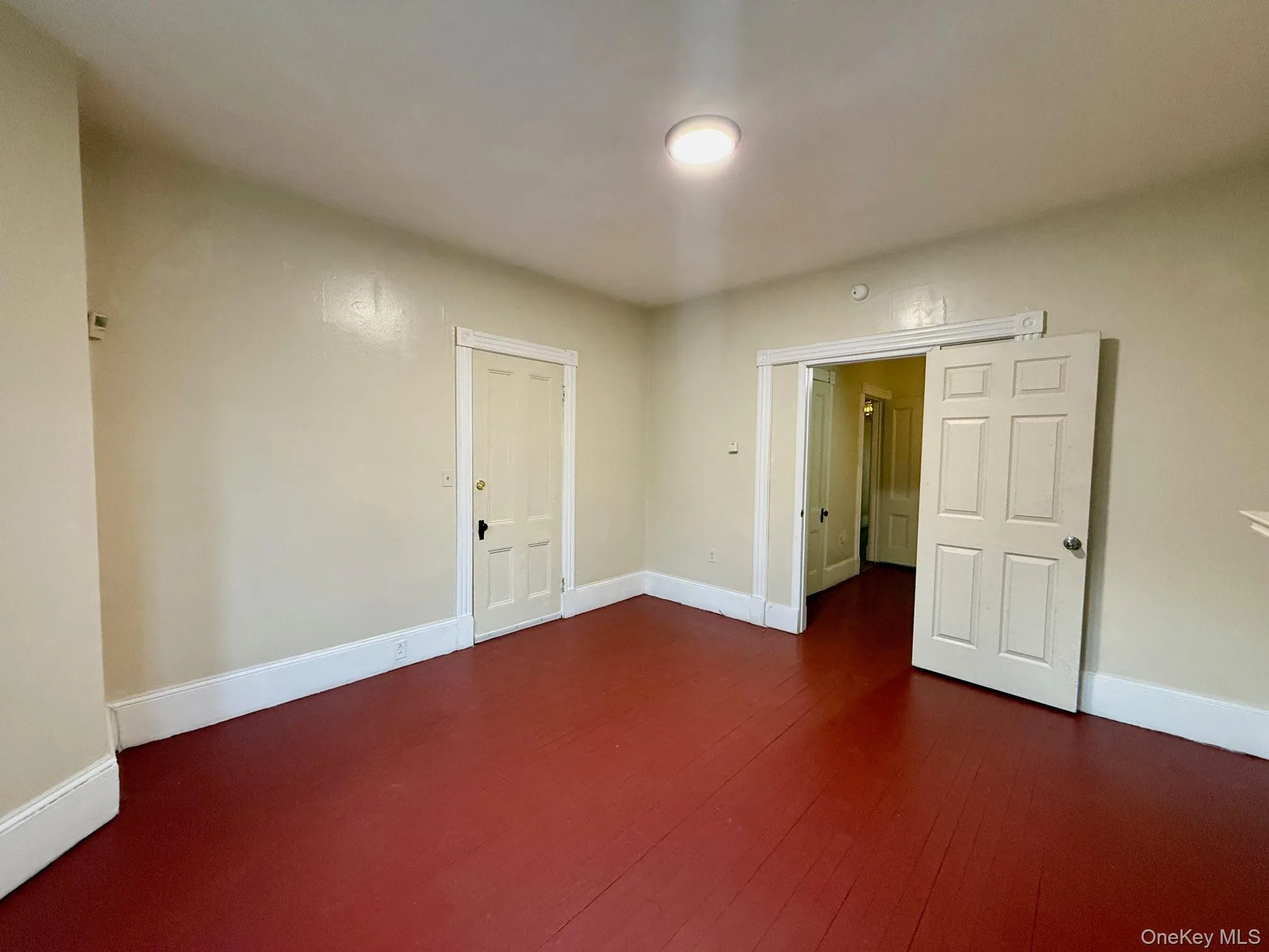 Unfurnished room with baseboards and dark wood-type flooring Unfurnished room with baseboards and dark wood-type flooring