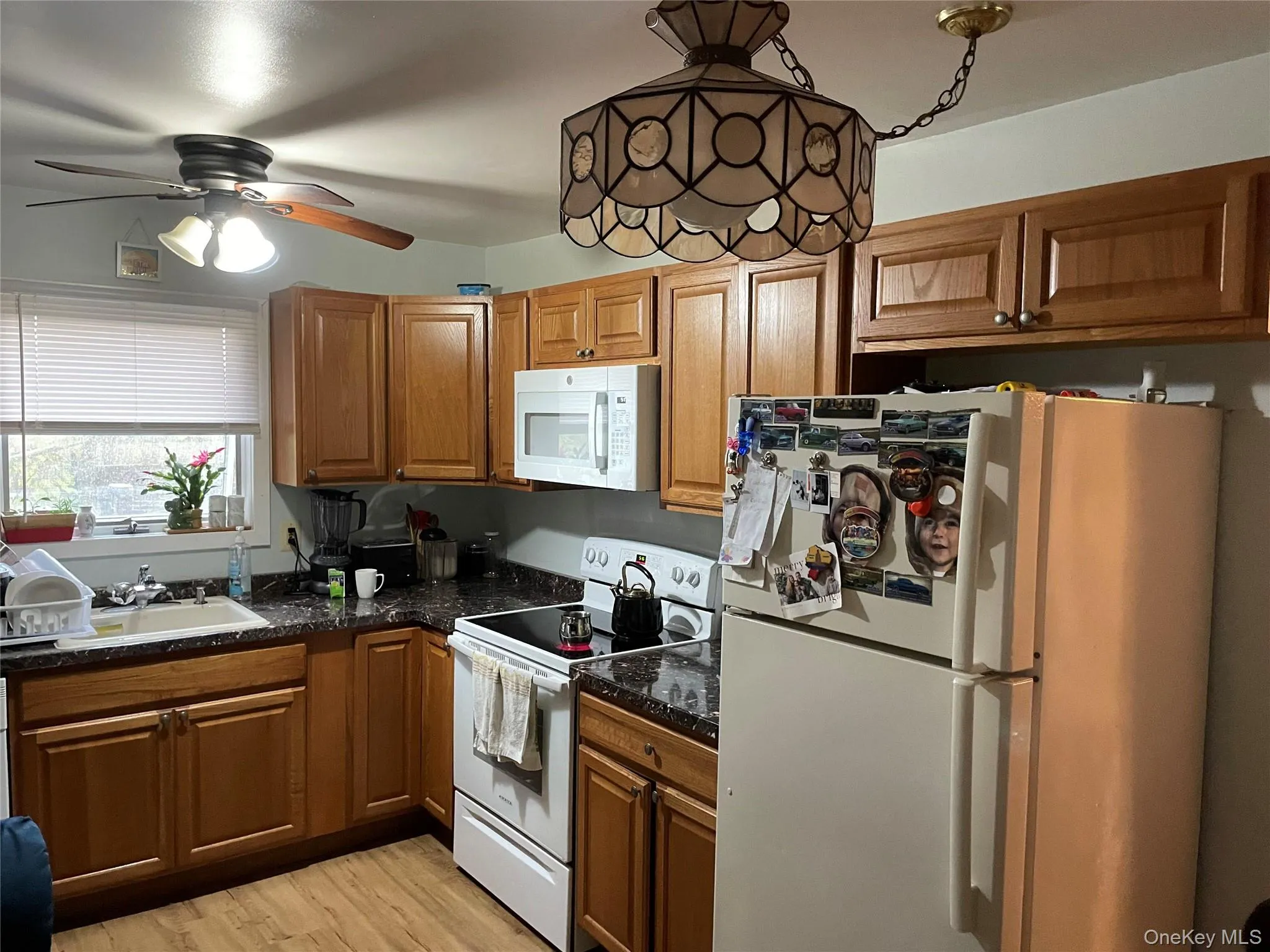 Kitchen featuring white appliances, brown cabinetry, and light wood finished floors Kitchen featuring white appliances, brown cabinetry, and light wood finished floors