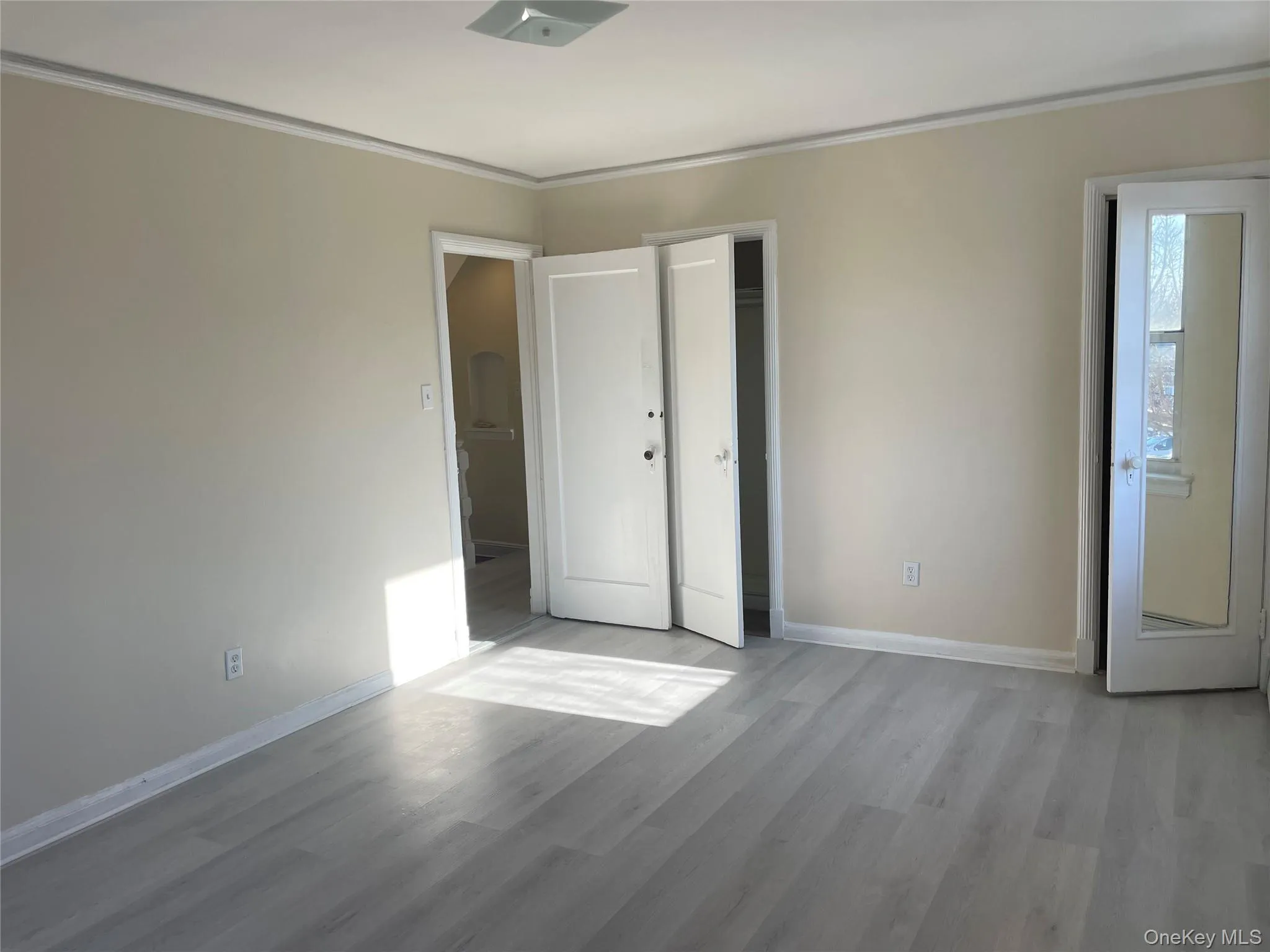 Unfurnished bedroom with ornamental molding and light wood-style floors Unfurnished bedroom with ornamental molding and light wood-style floors