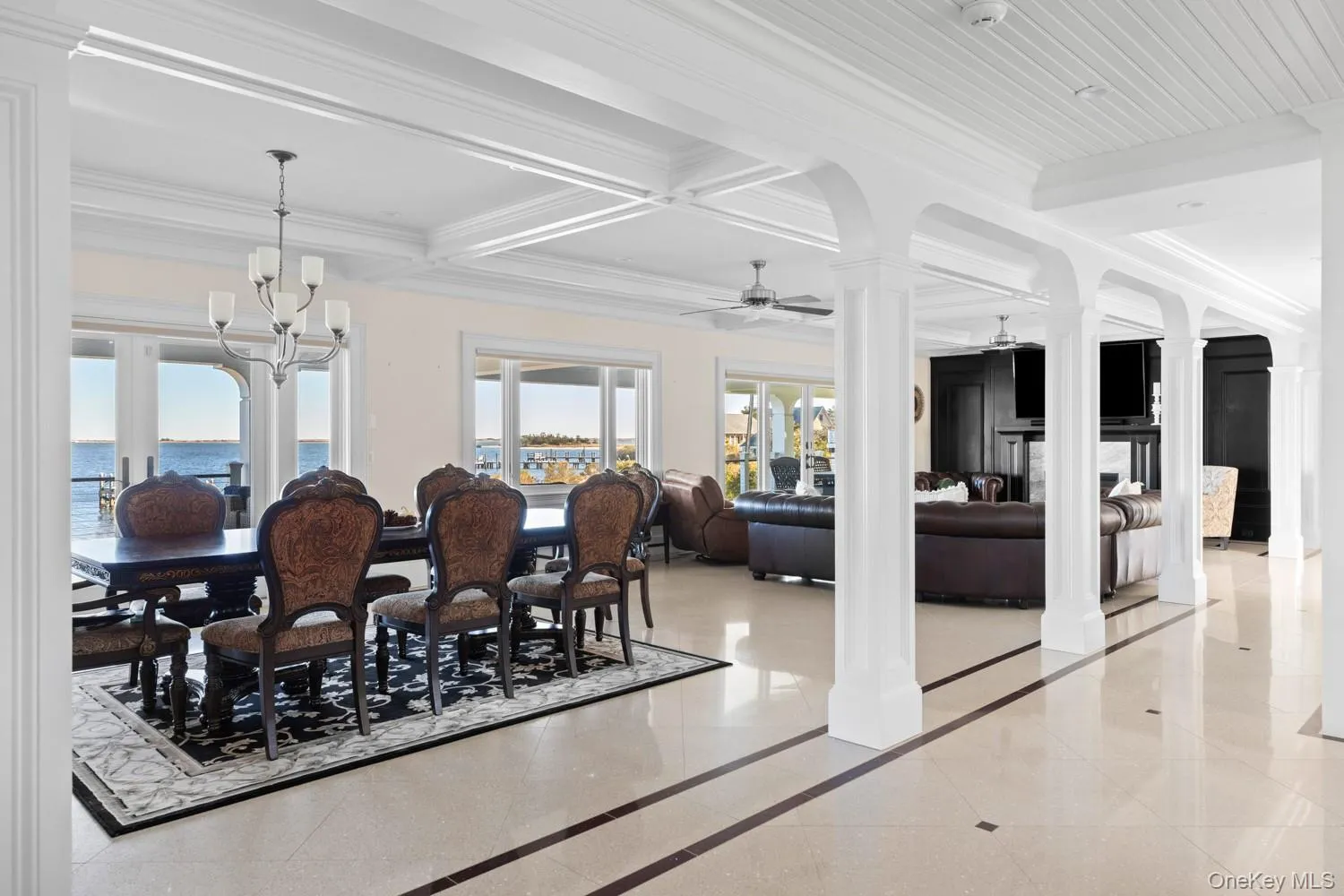 Dining area featuring decorative columns, ornamental molding, a chandelier, inlaid floor details, and coffered ceiling Dining area featuring decorative columns, ornamental molding, a chandelier, inlaid floor details, and coffered ceiling
