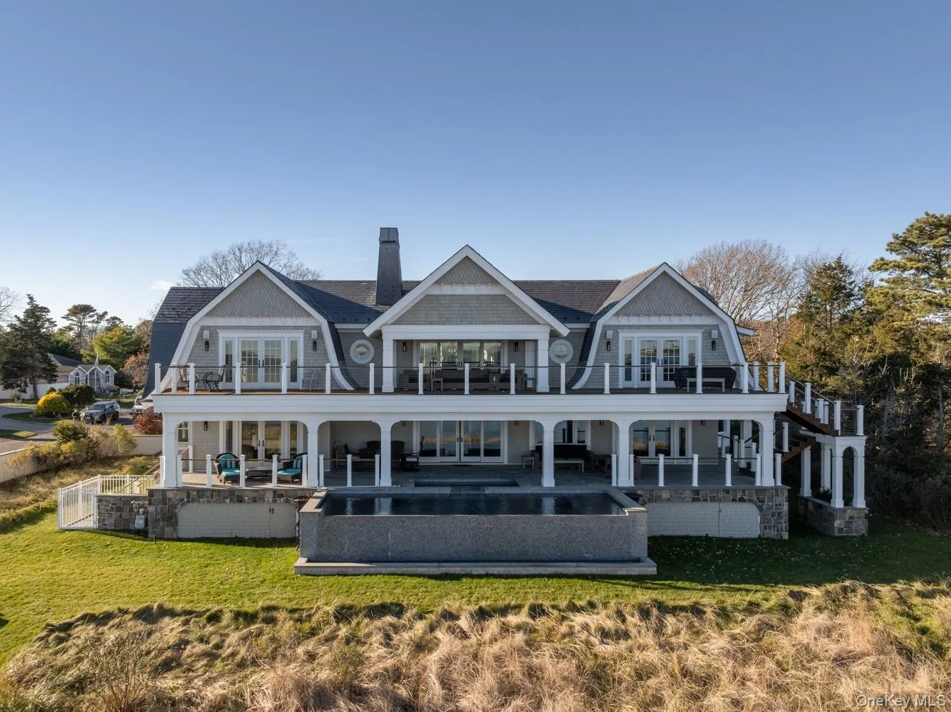 Back of house featuring a gambrel roof, french doors, a chimney, and covered porch Back of house featuring a gambrel roof, french doors, a chimney, and covered porch