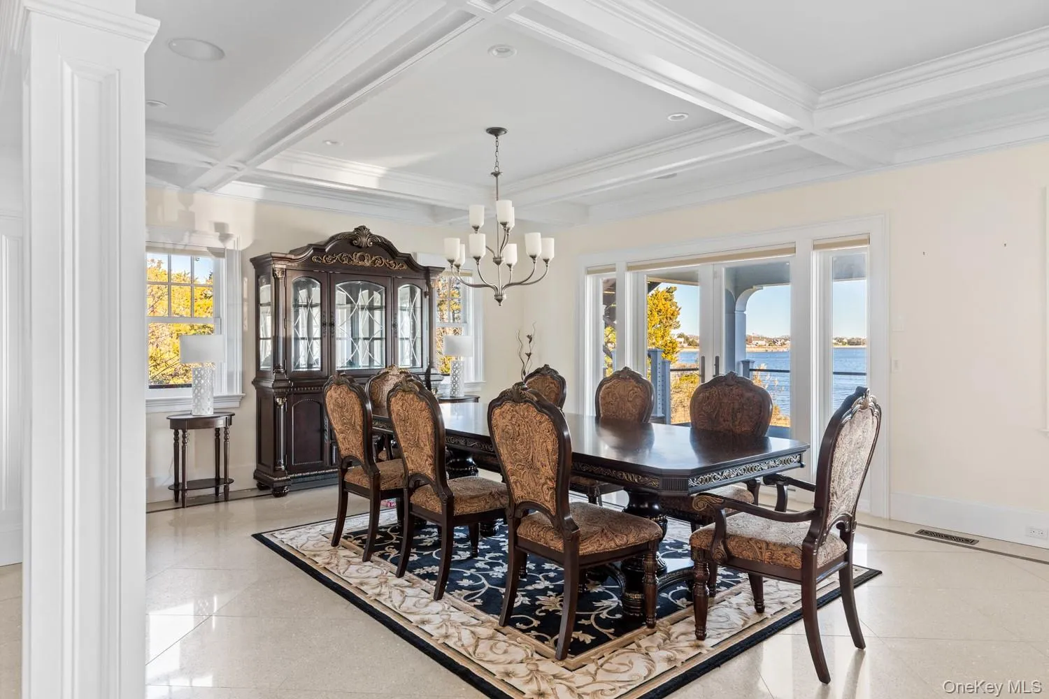Dining area with crown molding, coffered ceiling, beam ceiling, a water view, and a chandelier Dining area with crown molding, coffered ceiling, beam ceiling, a water view, and a chandelier
