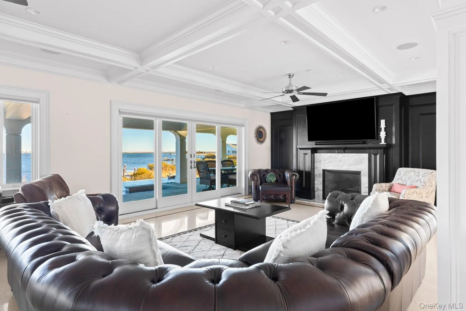 Living room with crown molding, coffered ceiling, a premium fireplace, beam ceiling, and a ceiling fan Living room with crown molding, coffered ceiling, a premium fireplace, beam ceiling, and a ceiling fan