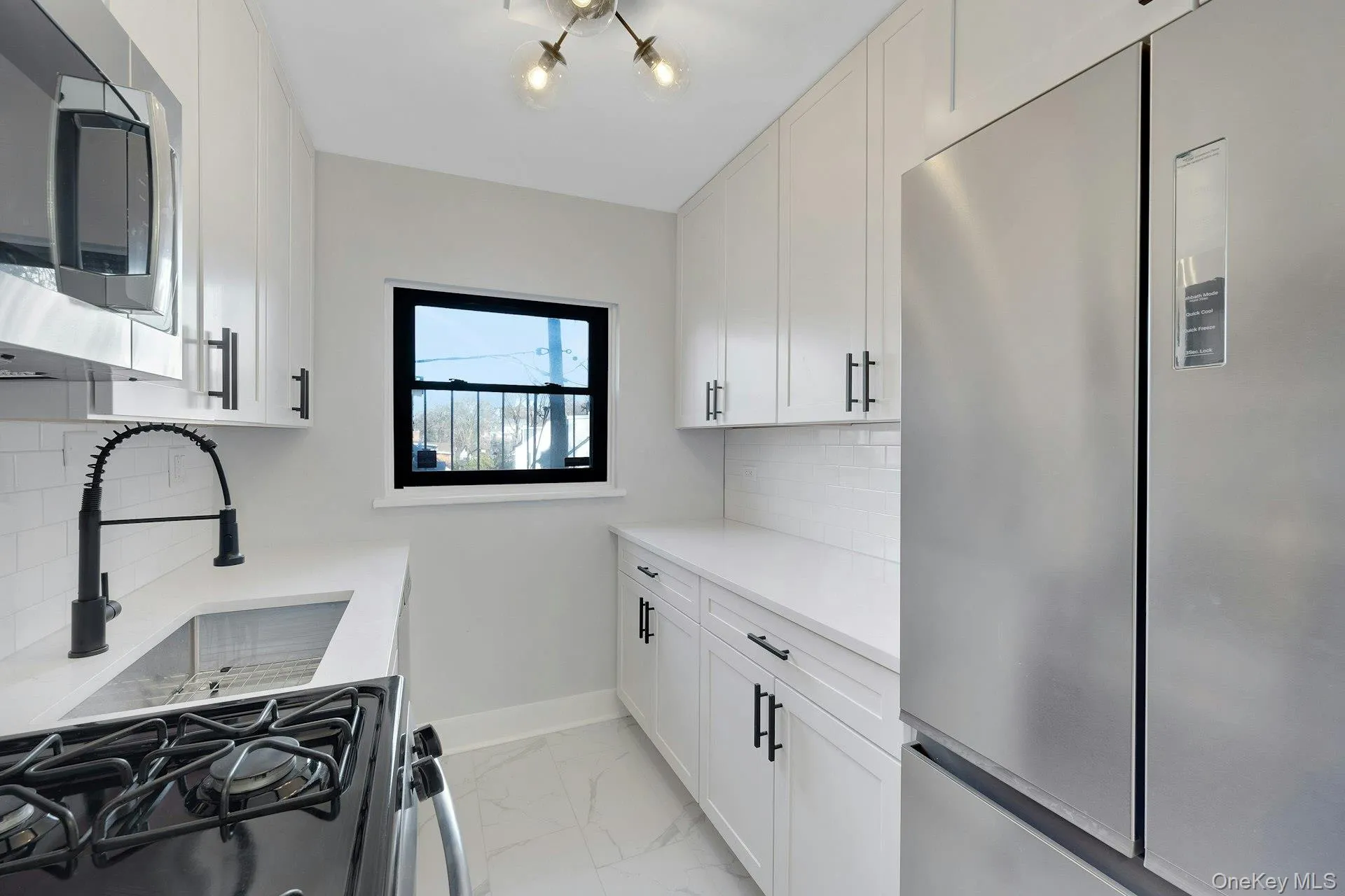 Kitchen with stainless steel appliances, white cabinetry, and light stone counters Kitchen with stainless steel appliances, white cabinetry, and light stone counters