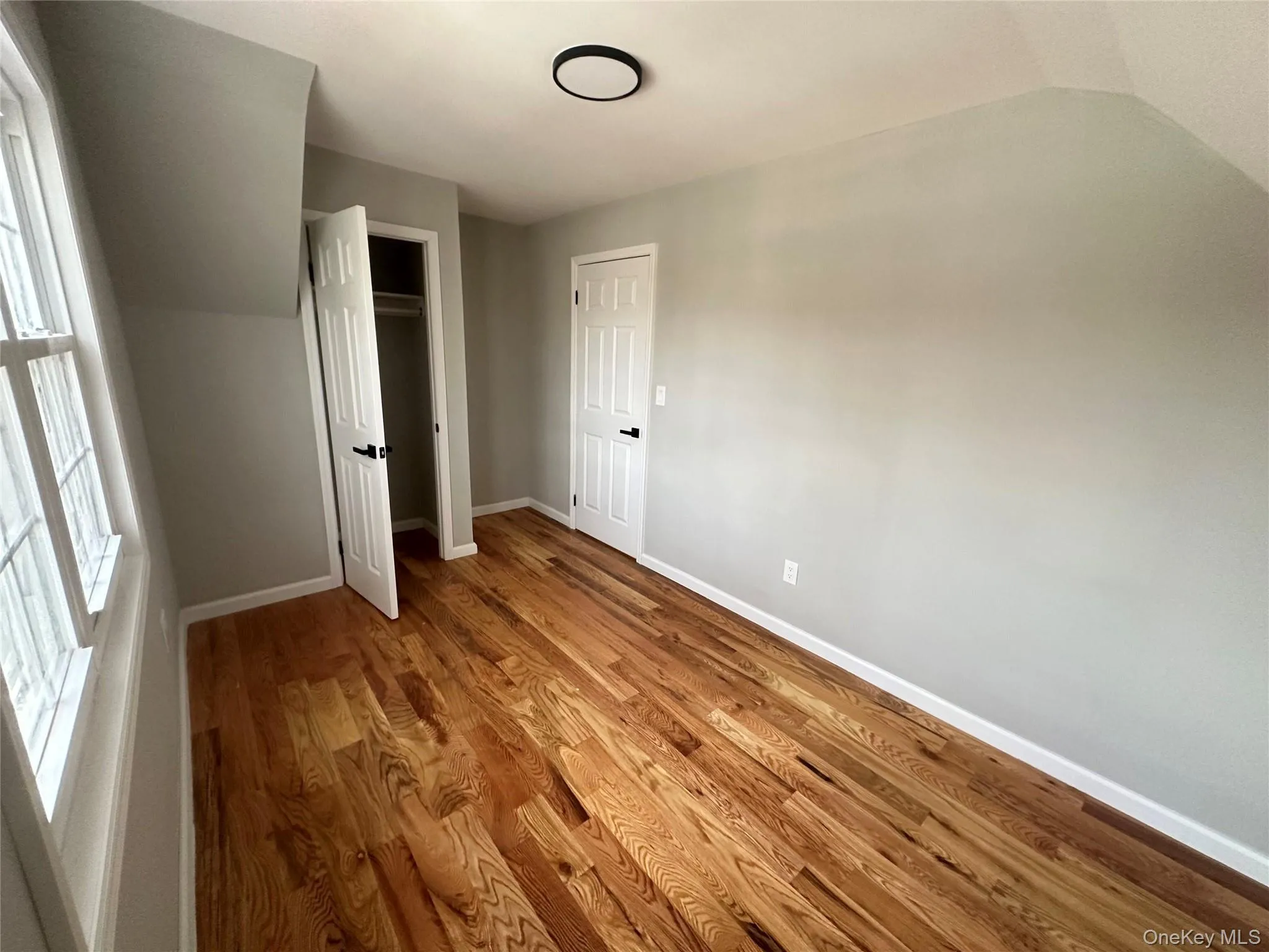 Unfurnished bedroom with light wood-style floors, vaulted ceiling, and a closet Unfurnished bedroom with light wood-style floors, vaulted ceiling, and a closet
