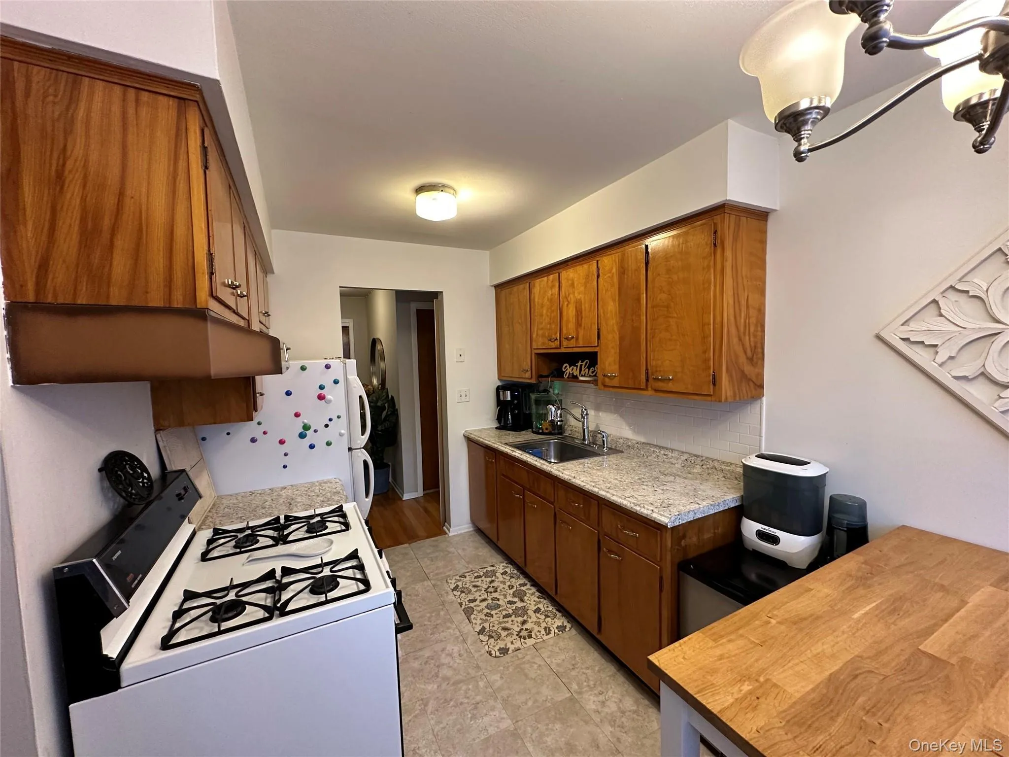 Kitchen featuring white appliances, brown cabinetry, decorative backsplash, and wooden counters Kitchen featuring white appliances, brown cabinetry, decorative backsplash, and wooden counters