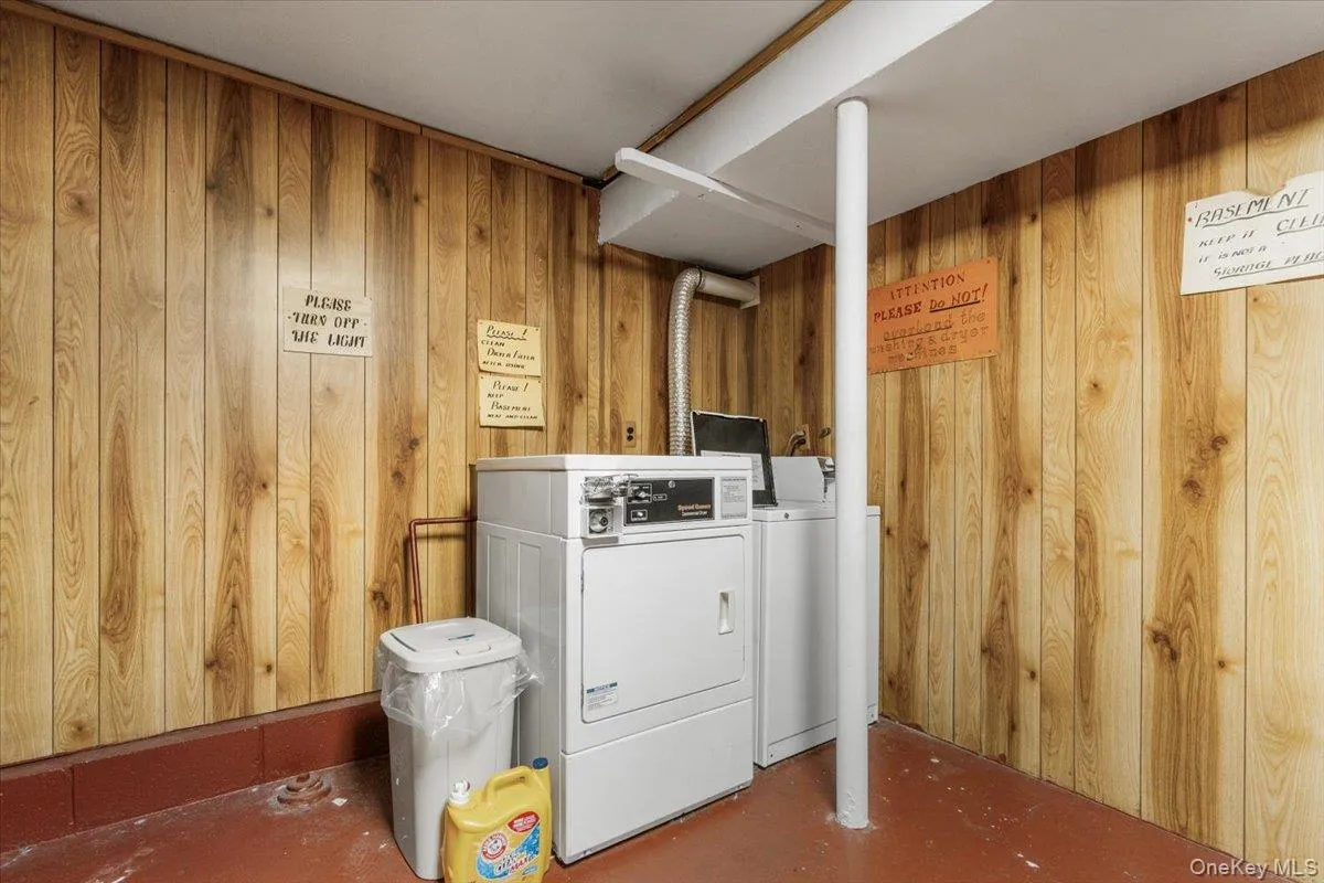 Laundry room featuring wood walls and separate washer and dryer Laundry room featuring wood walls and separate washer and dryer