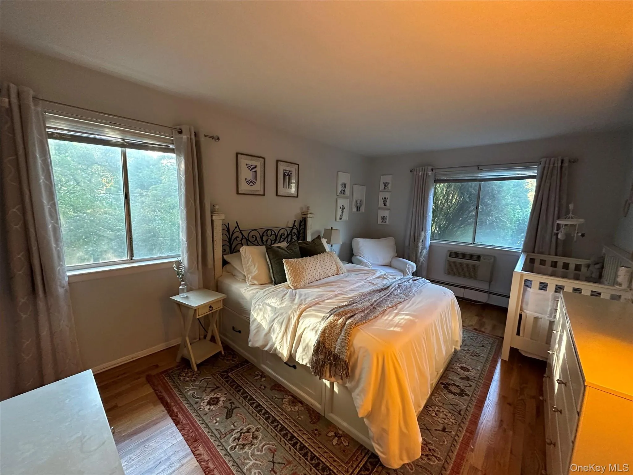 Bedroom with baseboard heating, dark wood-style flooring, and a wall mounted air conditioner Bedroom with baseboard heating, dark wood-style flooring, and a wall mounted air conditioner