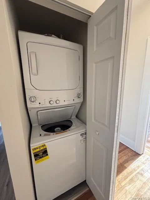 Laundry area with light wood finished floors and estacked washer and dryer Laundry area with light wood finished floors and estacked washer and dryer