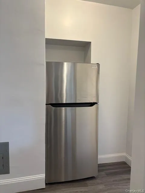 Kitchen view of freestanding refrigerator and dark wood-style flooring Kitchen view of freestanding refrigerator and dark wood-style flooring