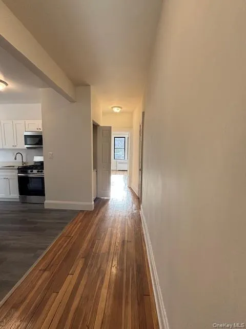 Corridor featuring dark wood-style flooring and baseboards Corridor featuring dark wood-style flooring and baseboards