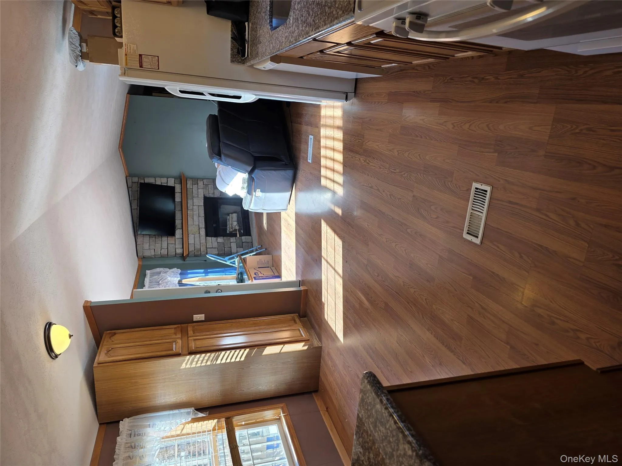 Kitchen featuring a brick fireplace, vaulted ceiling, fridge, dark wood finished floors, and brown cabinets Kitchen featuring a brick fireplace, vaulted ceiling, fridge, dark wood finished floors, and brown cabinets