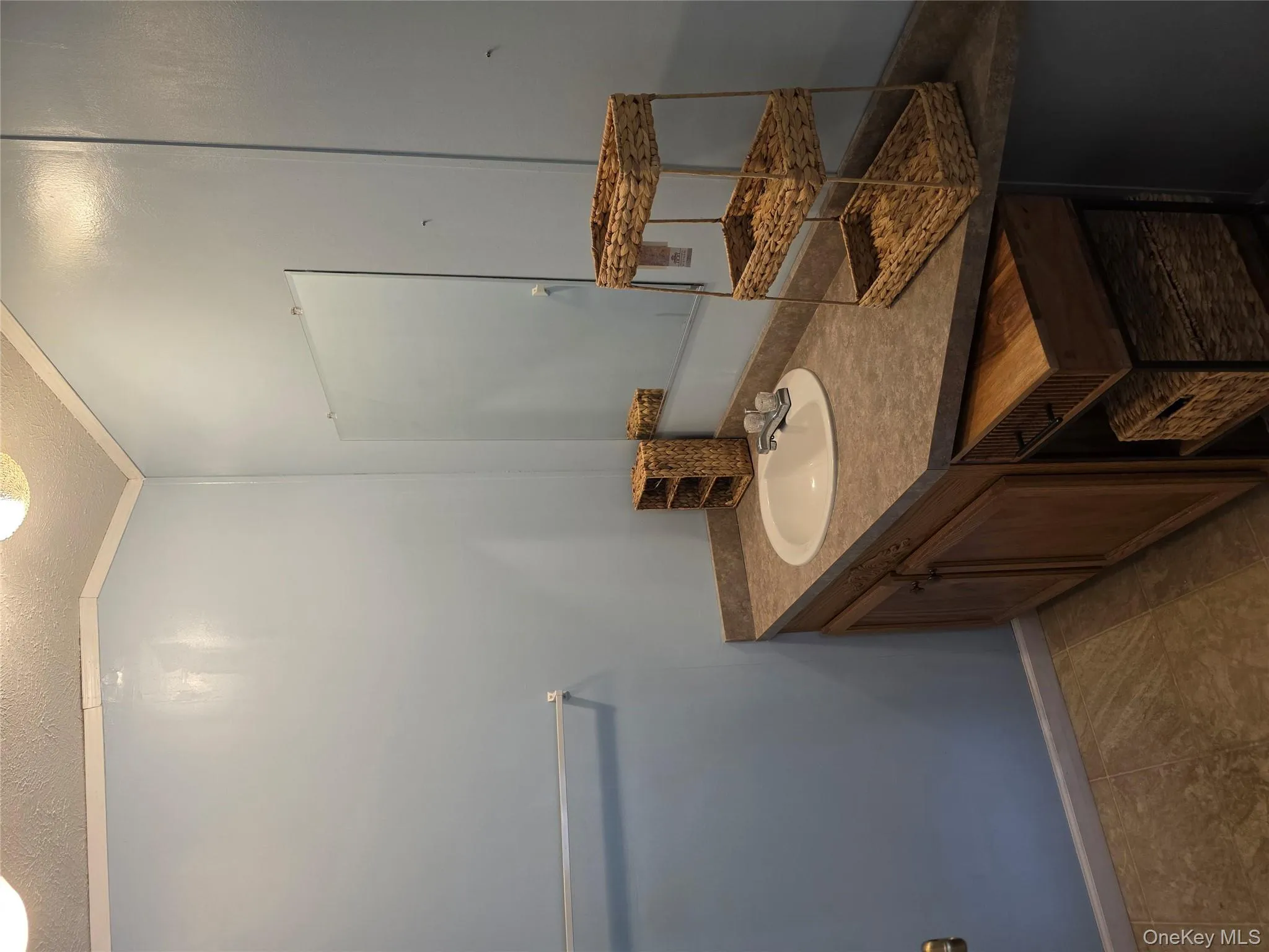 Half bathroom featuring vanity, a textured ceiling, ornamental molding, and light tile patterned floors Half bathroom featuring vanity, a textured ceiling, ornamental molding, and light tile patterned floors