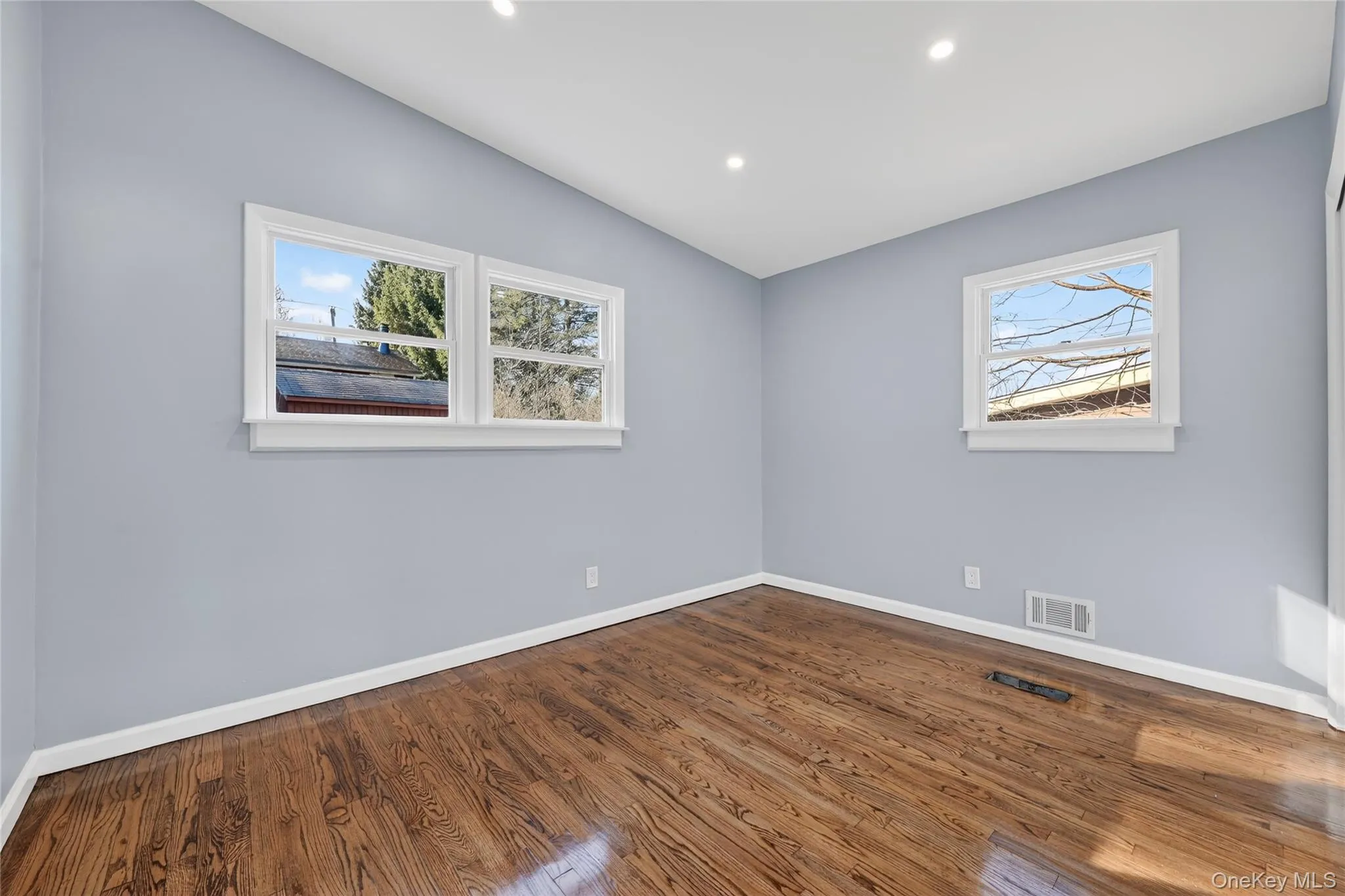 Spare room with healthy amount of natural light, dark wood-style flooring, recessed lighting, and vaulted ceiling Spare room with healthy amount of natural light, dark wood-style flooring, recessed lighting, and vaulted ceiling