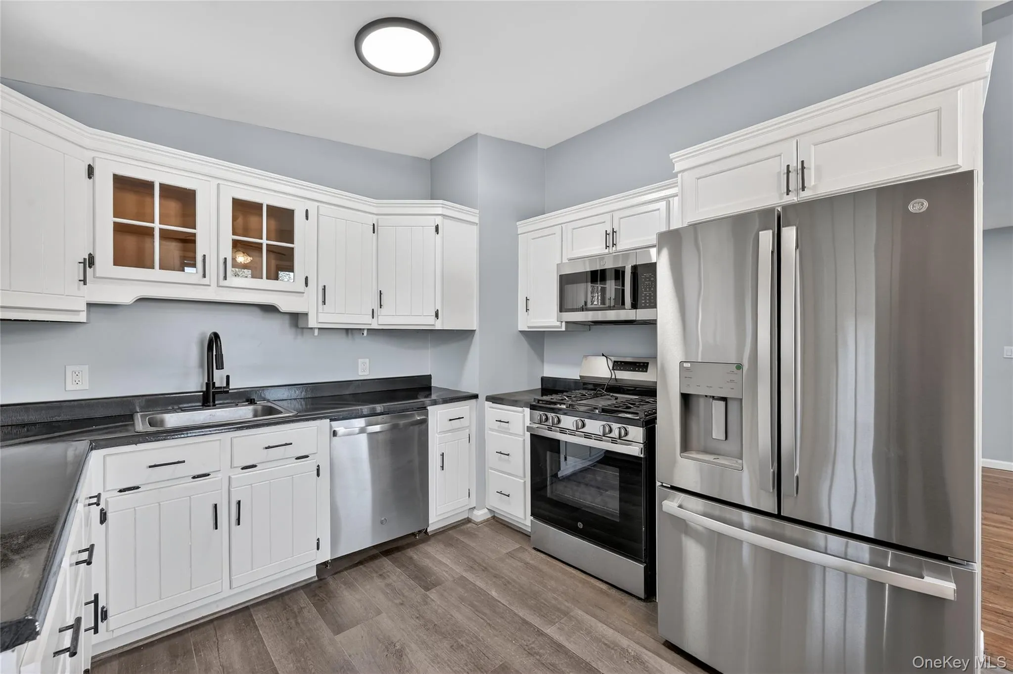 Kitchen with stainless steel appliances, dark countertops, and white cabinetry Kitchen with stainless steel appliances, dark countertops, and white cabinetry