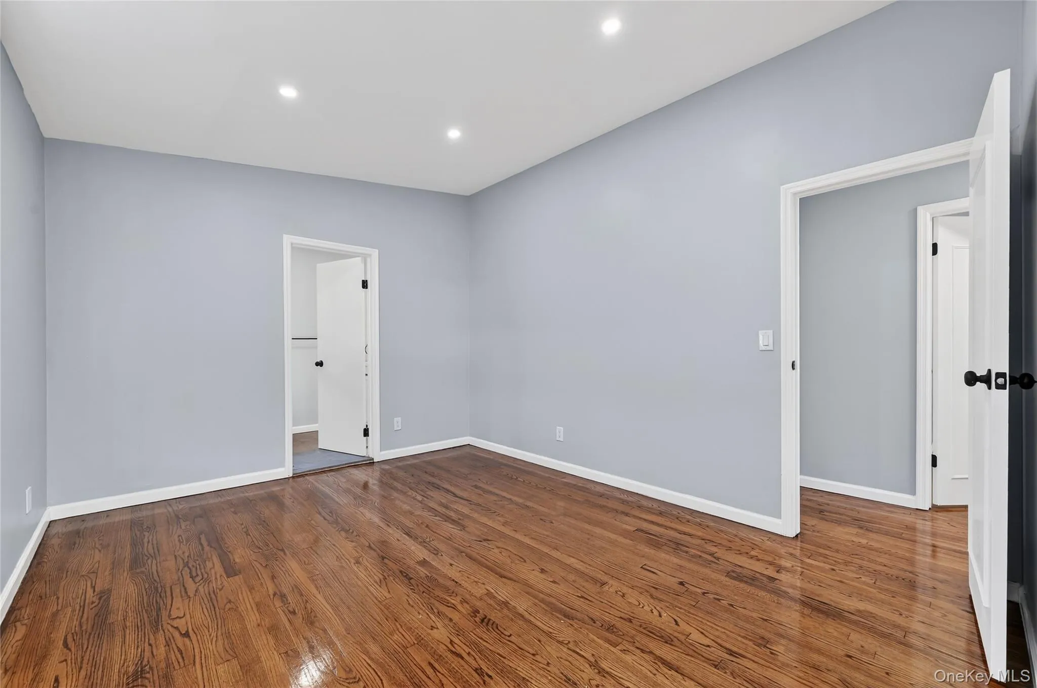 Unfurnished bedroom with dark wood-style floors and recessed lighting Unfurnished bedroom with dark wood-style floors and recessed lighting