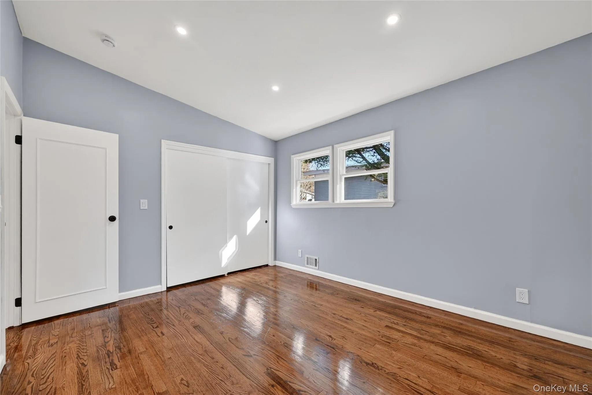 Unfurnished bedroom with a closet, hardwood / wood-style flooring, vaulted ceiling, and recessed lighting Unfurnished bedroom with a closet, hardwood / wood-style flooring, vaulted ceiling, and recessed lighting