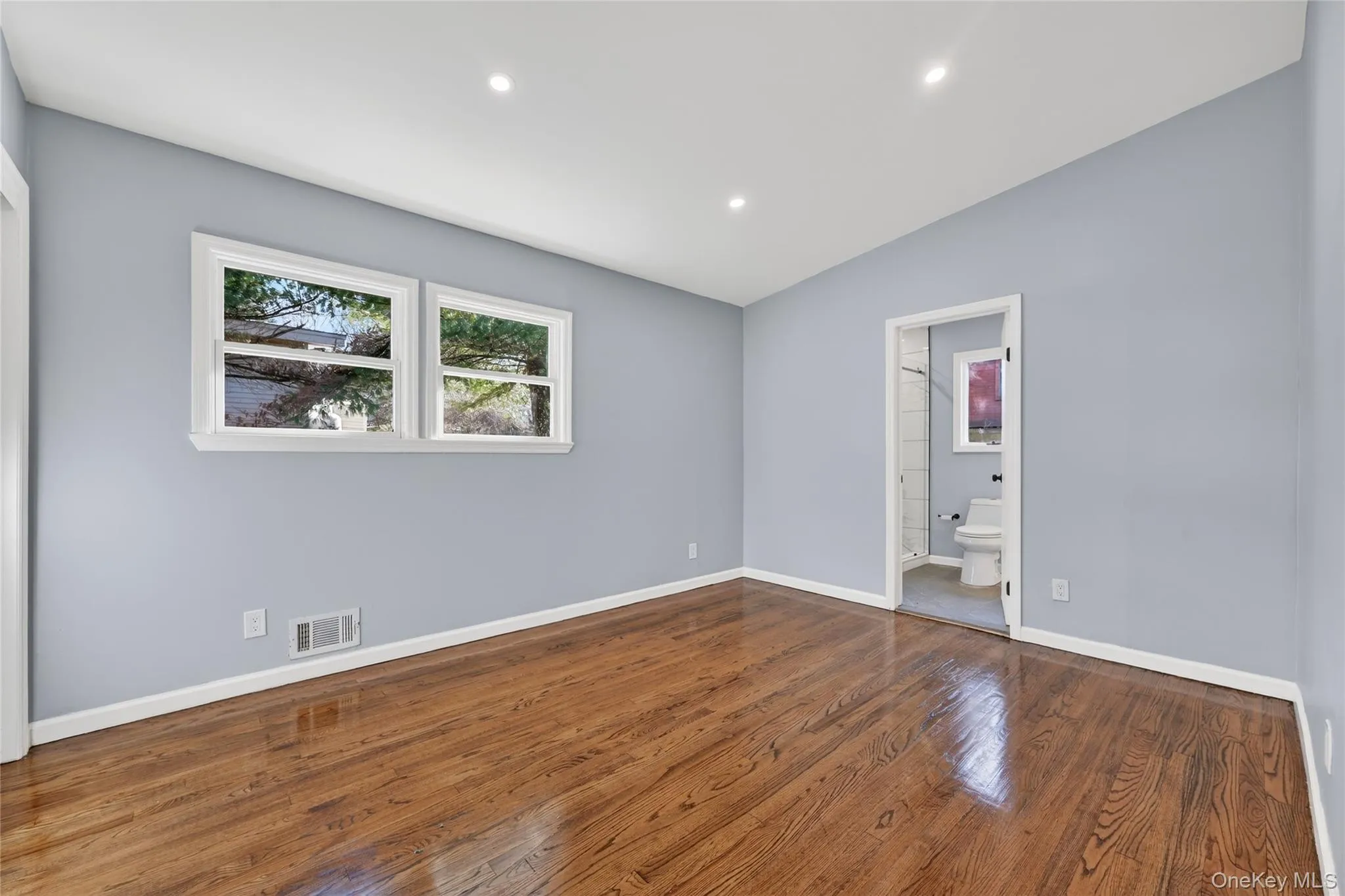 Unfurnished bedroom featuring recessed lighting, vaulted ceiling, dark wood-style floors, and ensuite bath Unfurnished bedroom featuring recessed lighting, vaulted ceiling, dark wood-style floors, and ensuite bath