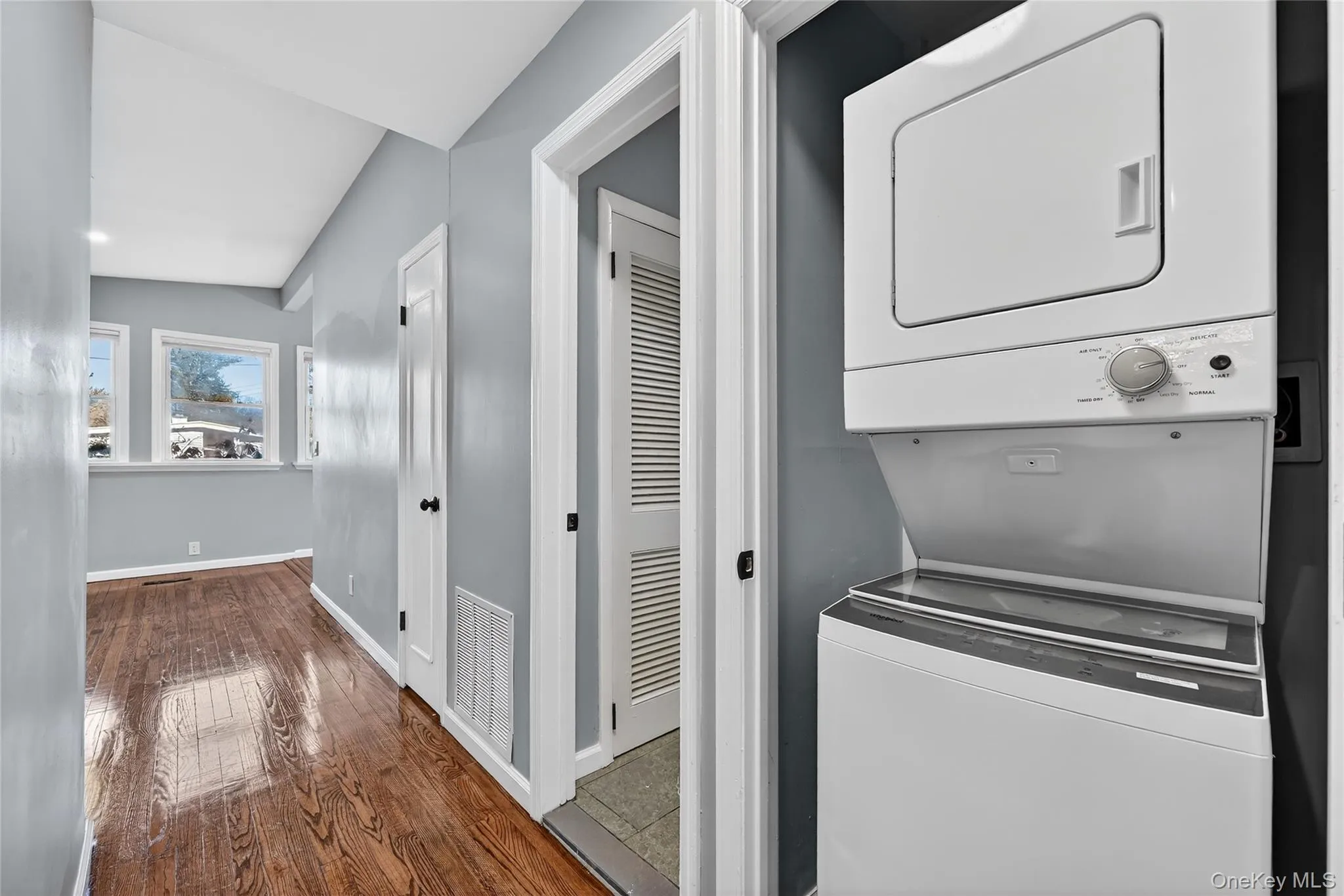 Laundry room featuring dark wood-style floors and stacked washer and clothes dryer Laundry room featuring dark wood-style floors and stacked washer and clothes dryer