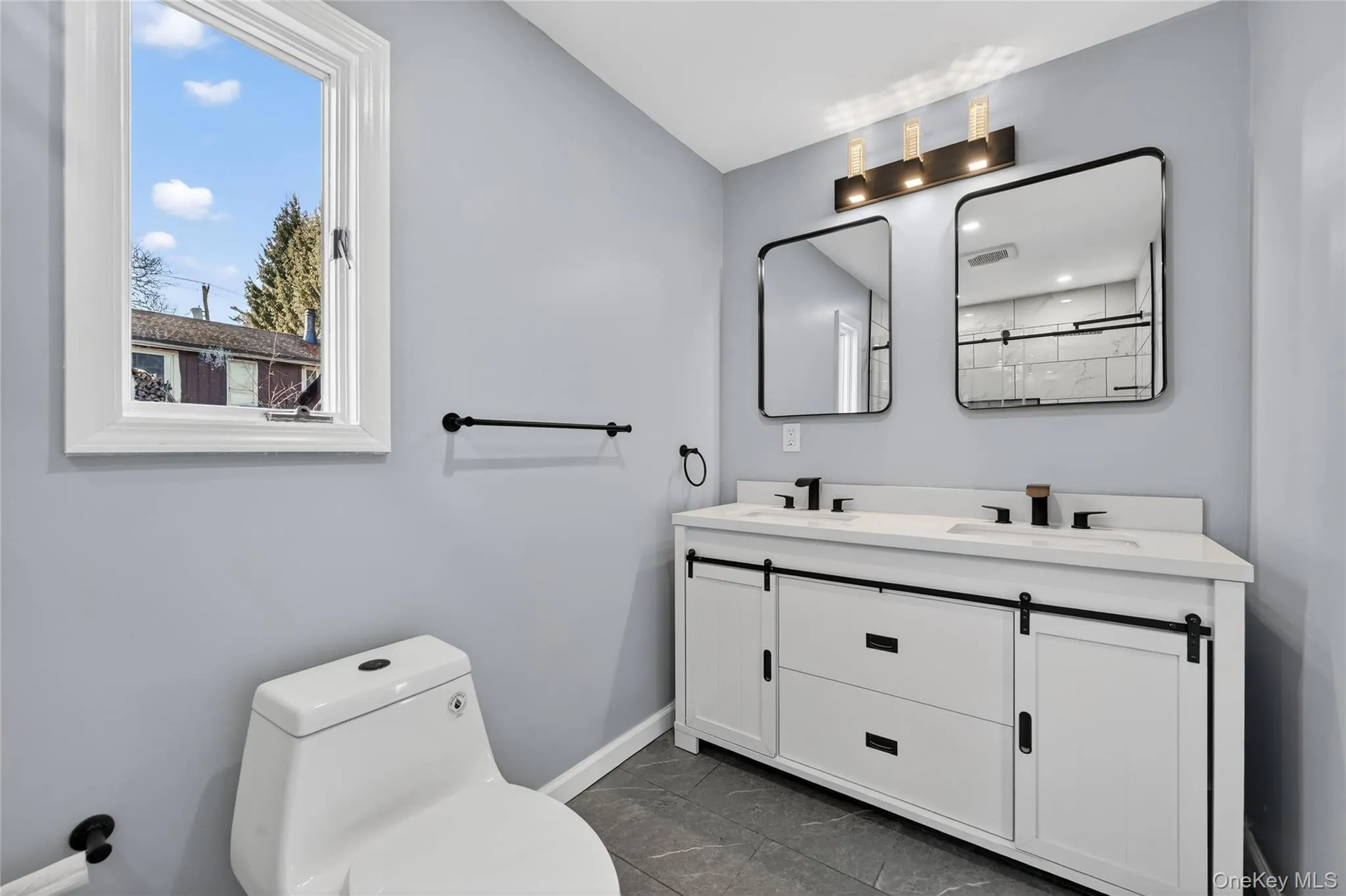 Bathroom featuring double vanity and dark marble finish flooring Bathroom featuring double vanity and dark marble finish flooring