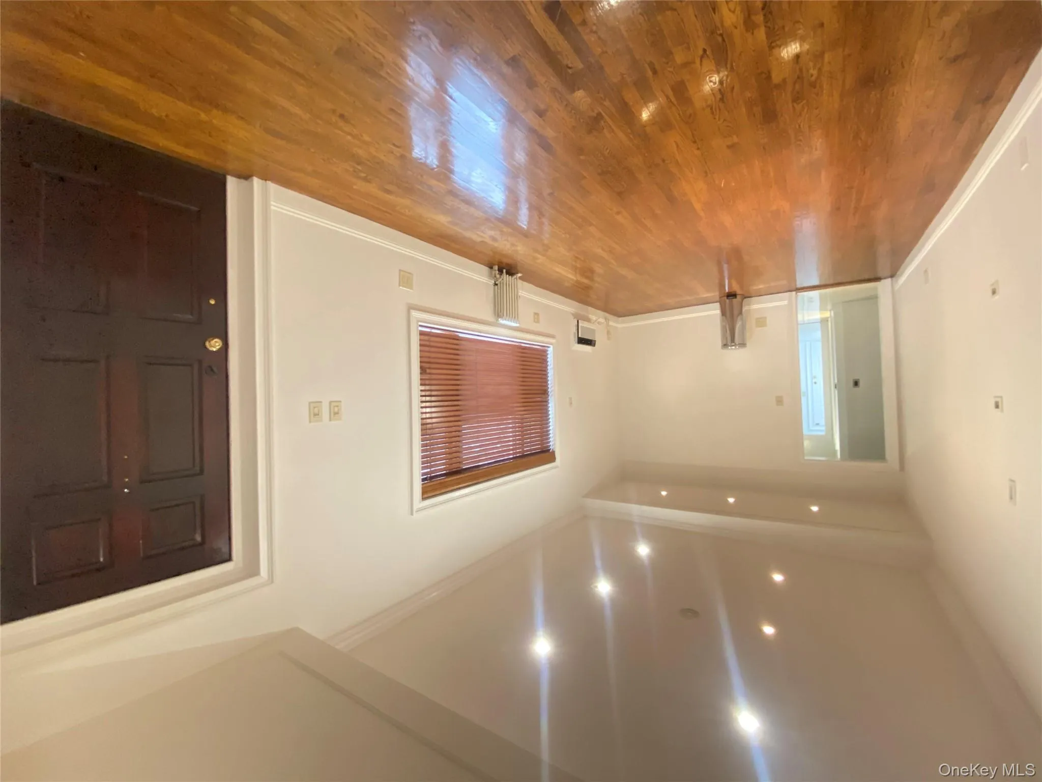 Unfurnished living room with wood finished floors, ornamental molding, recessed lighting, and radiator heating unit Unfurnished living room with wood finished floors, ornamental molding, recessed lighting, and radiator heating unit