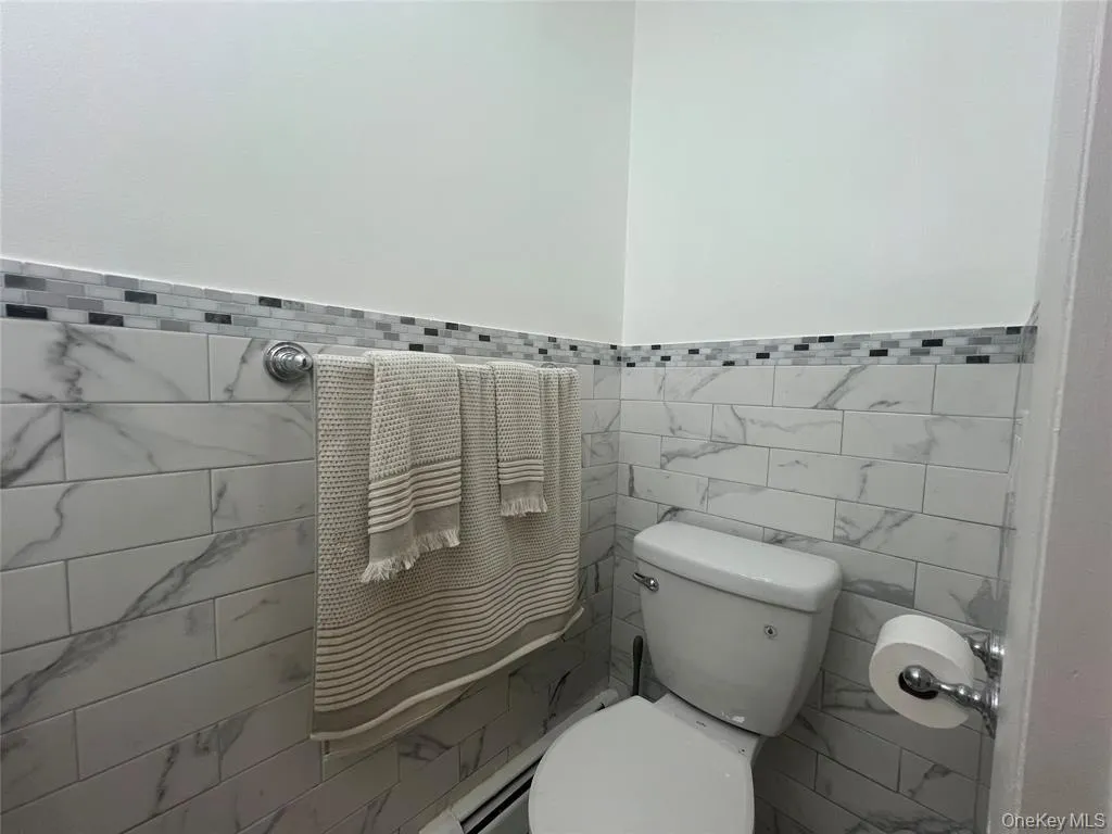 Half bathroom featuring toilet and tile walls Half bathroom featuring toilet and tile walls