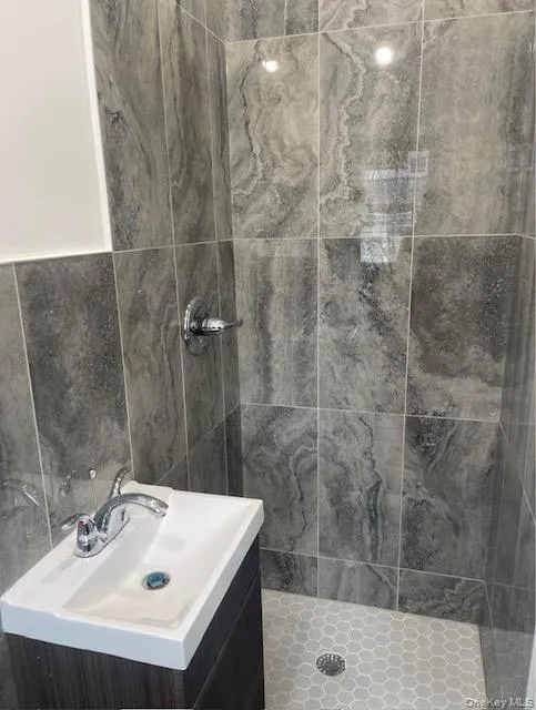 Bathroom with vanity, a stall shower, and tile walls Bathroom with vanity, a stall shower, and tile walls