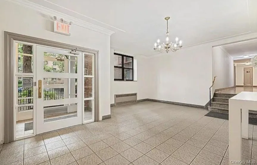 Unfurnished dining area featuring ornamental molding, stairs, radiator, and a chandelier Unfurnished dining area featuring ornamental molding, stairs, radiator, and a chandelier